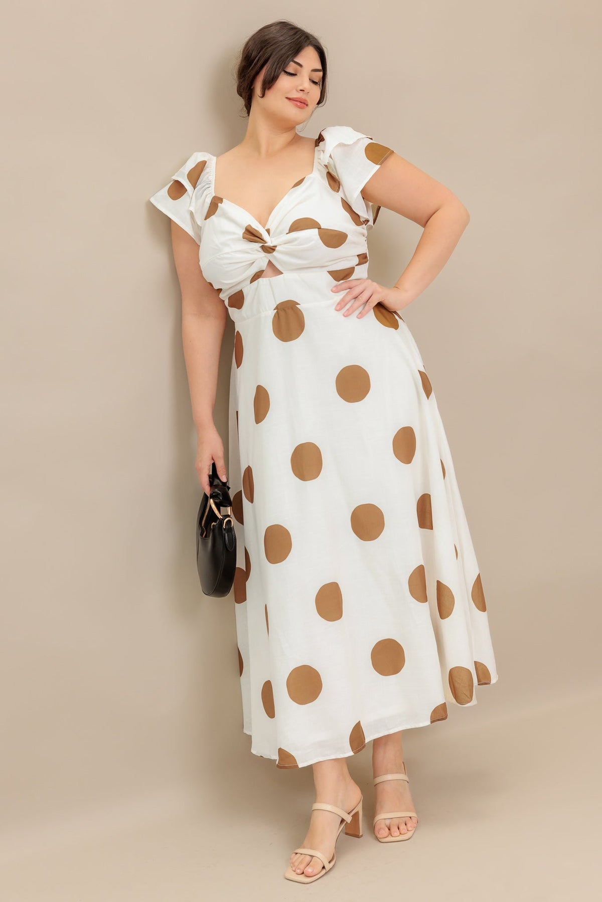 Woman wearing a white dress with brown polka dots against a beige background