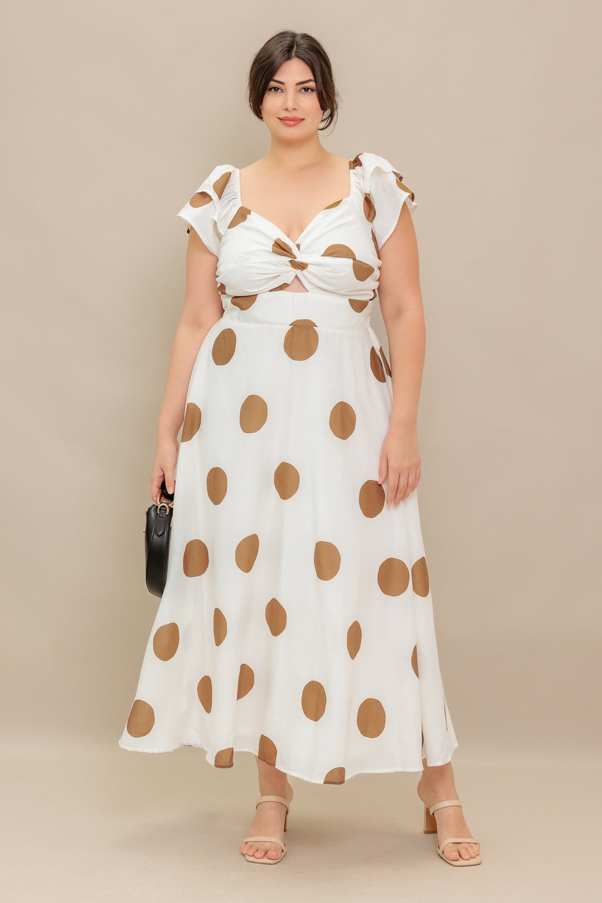 Woman wearing a white dress with brown polka dots against a beige background