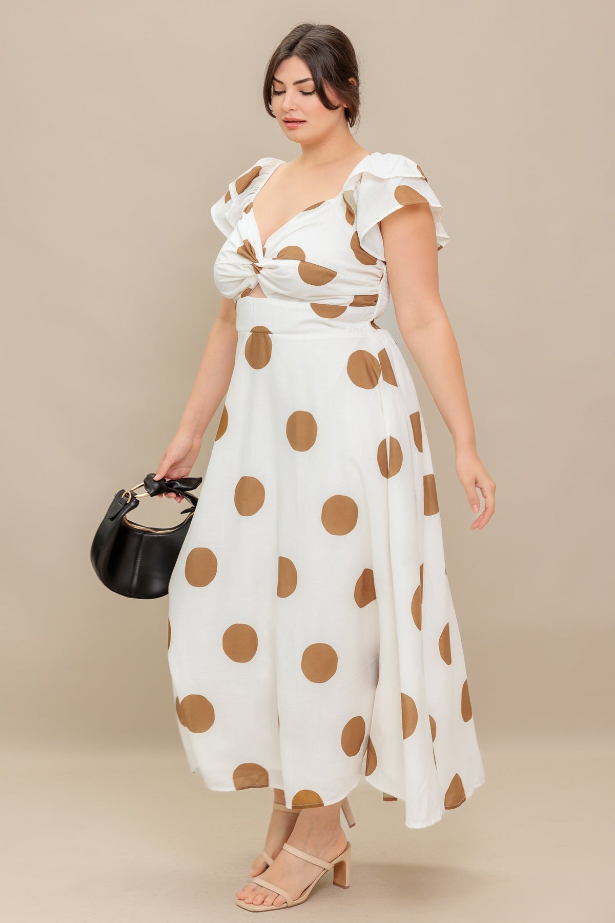Woman wearing a white dress with brown polka dots against a beige background
