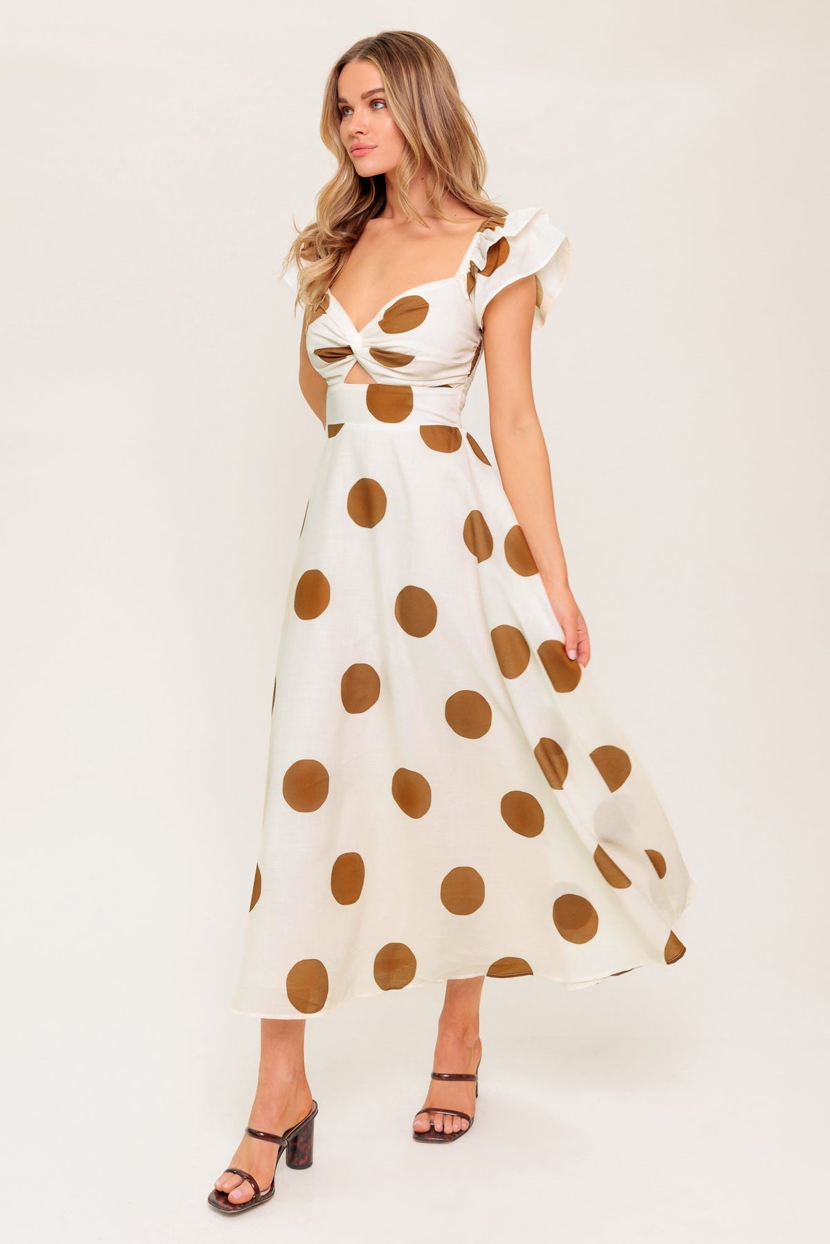 Woman wearing a white dress with brown polka dots on a white background