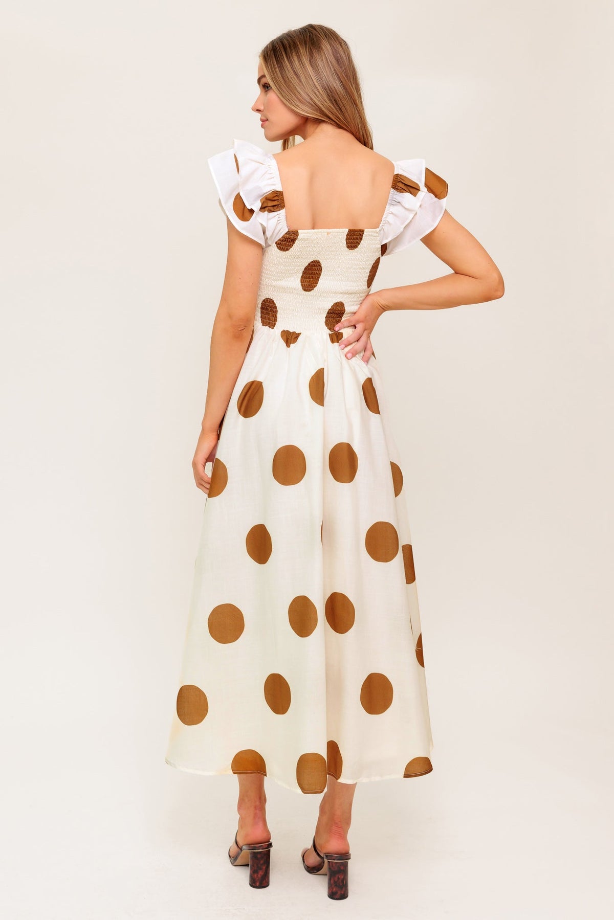Woman wearing a polka dot dress with a plain background