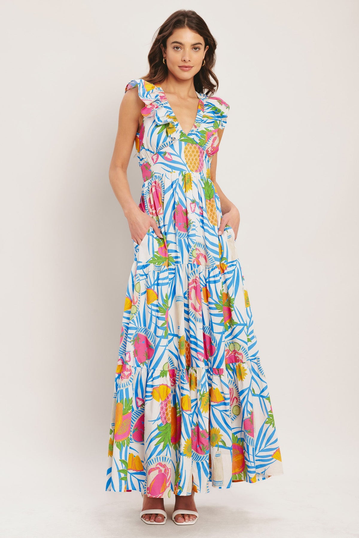 Woman wearing a colorful tropical print dress on a plain background