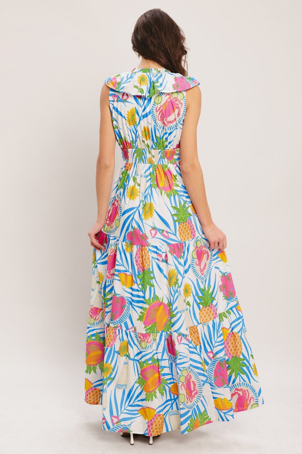 Woman wearing a colorful tropical patterned dress on a plain background