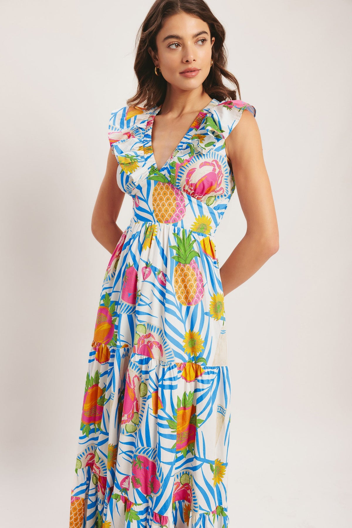 Woman wearing a colorful tropical print dress on a plain background