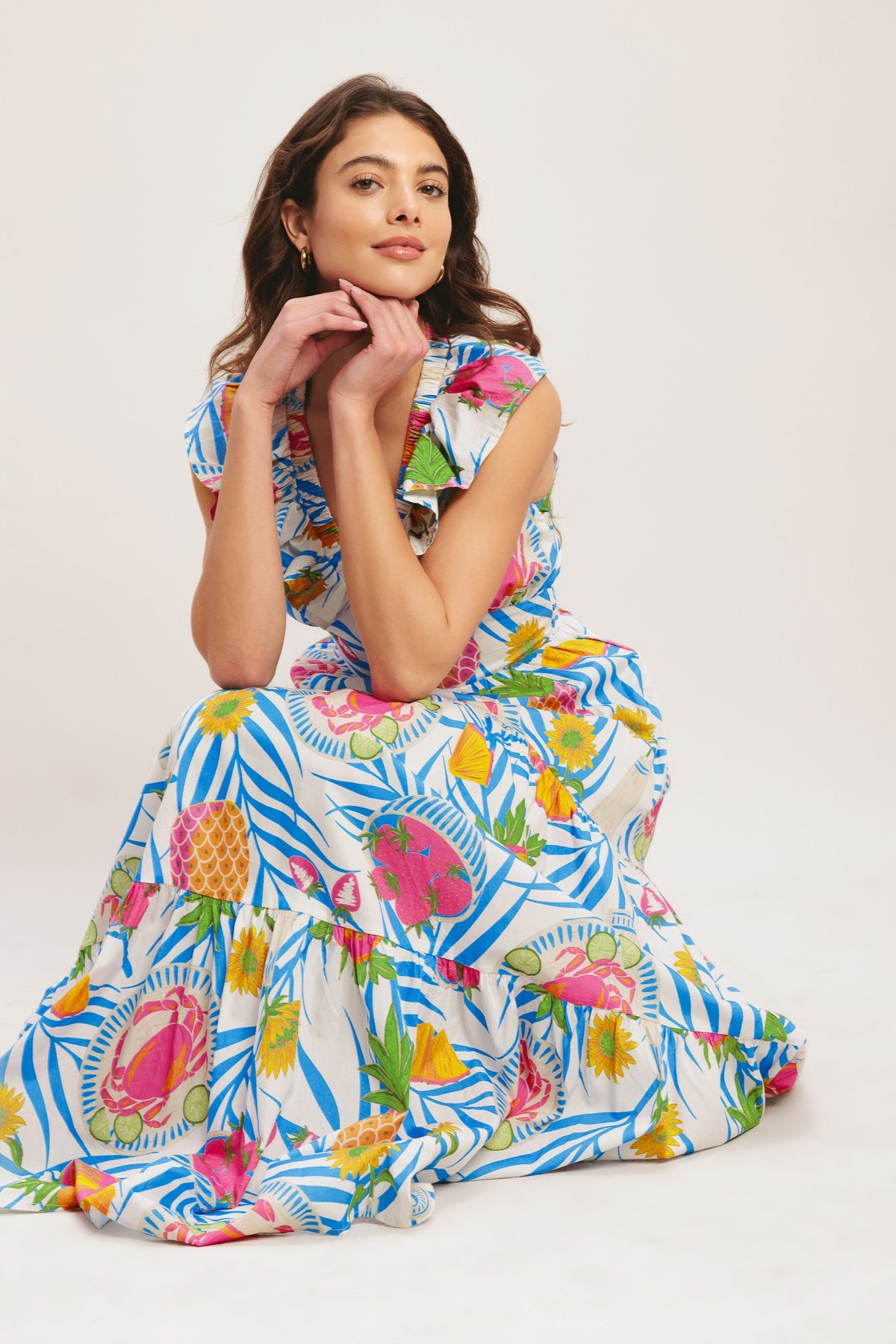 Woman wearing a colorful dress with a pattern of fruits and flowers on a white background