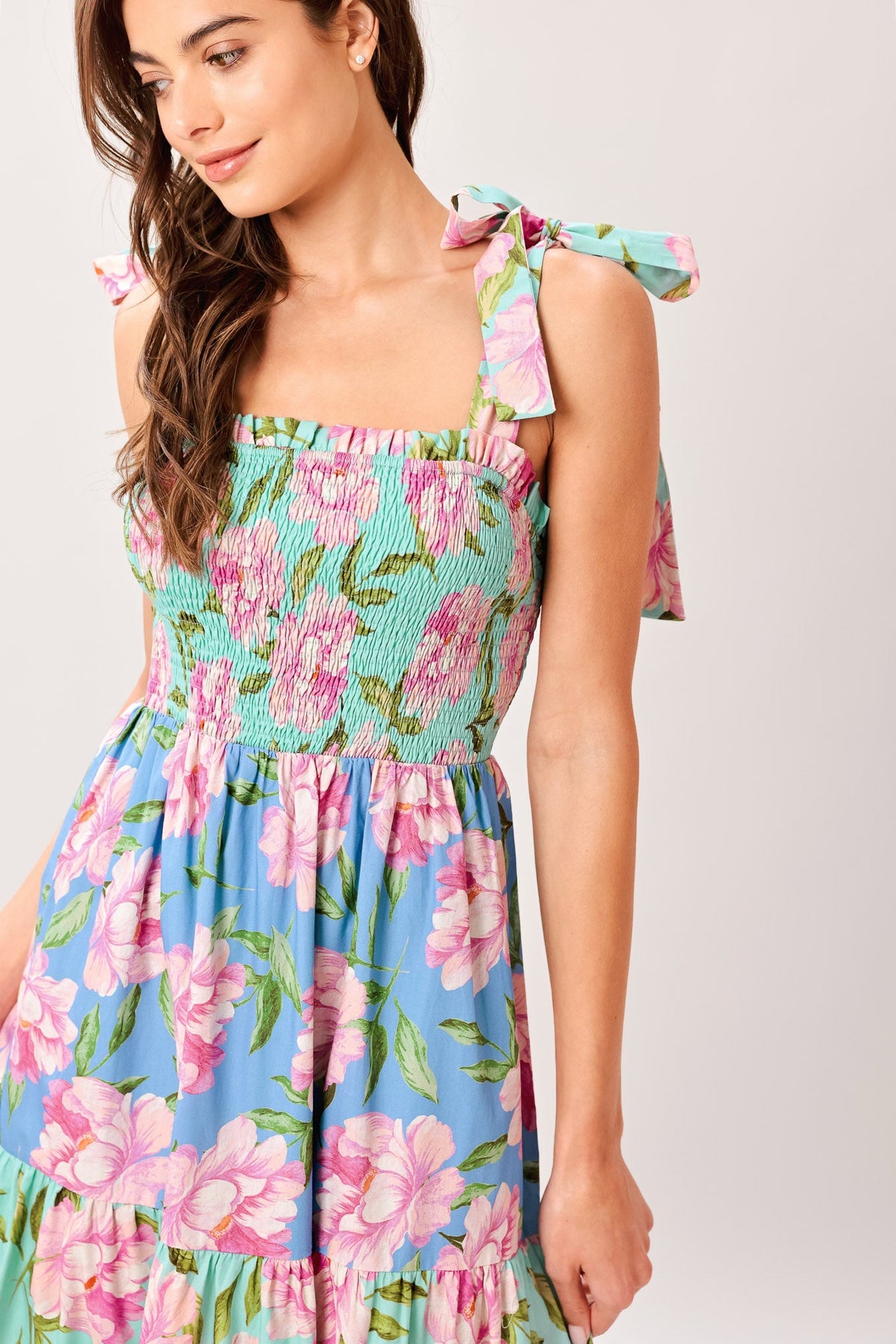 Woman wearing a colorful floral dress on a plain background
