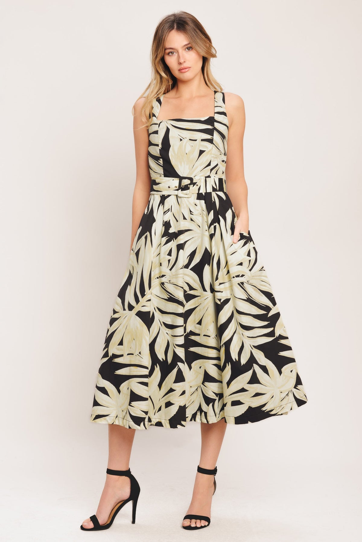 Woman wearing a black and white leaf-patterned dress on a plain background