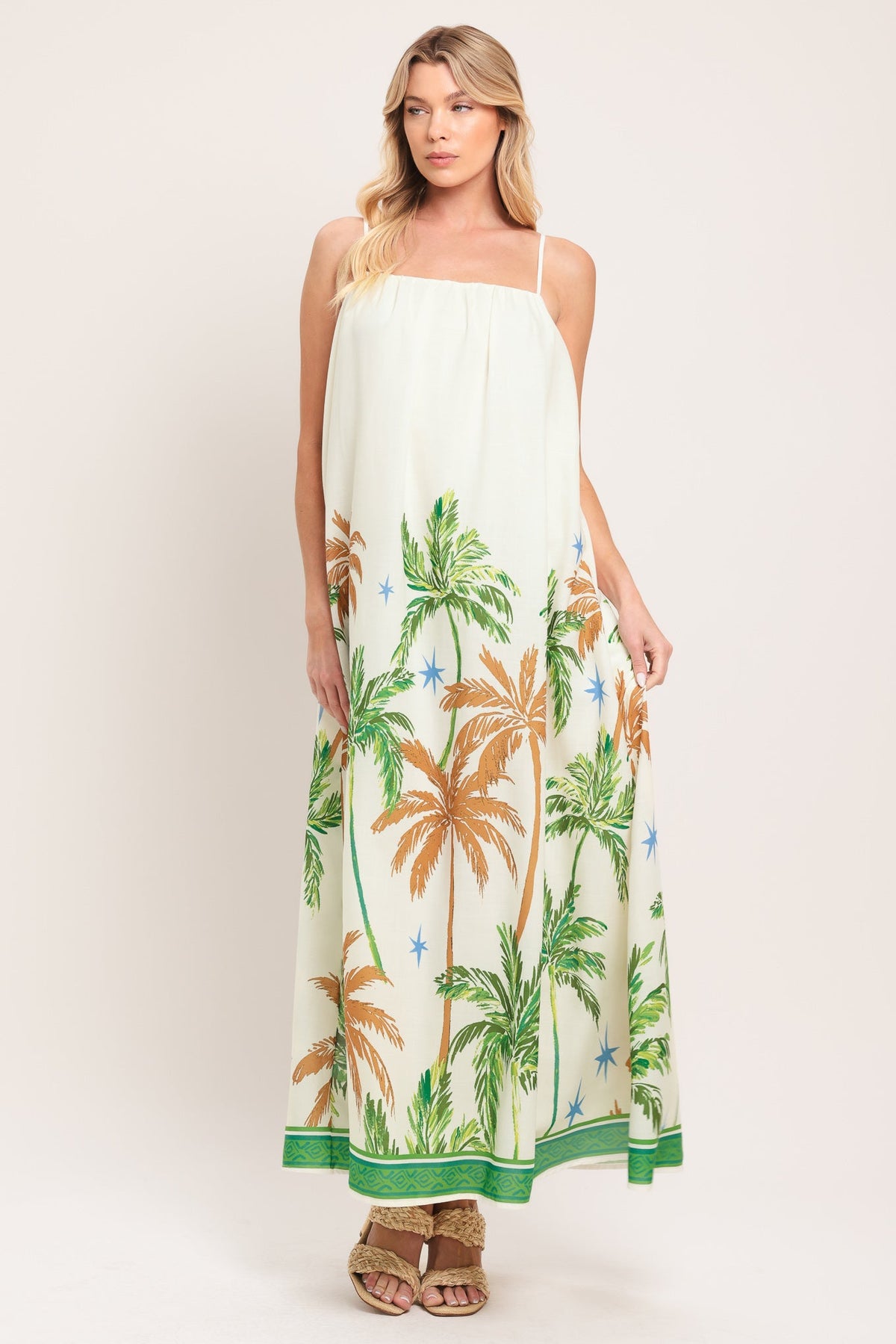 Woman wearing a white dress with palm tree pattern on a plain background