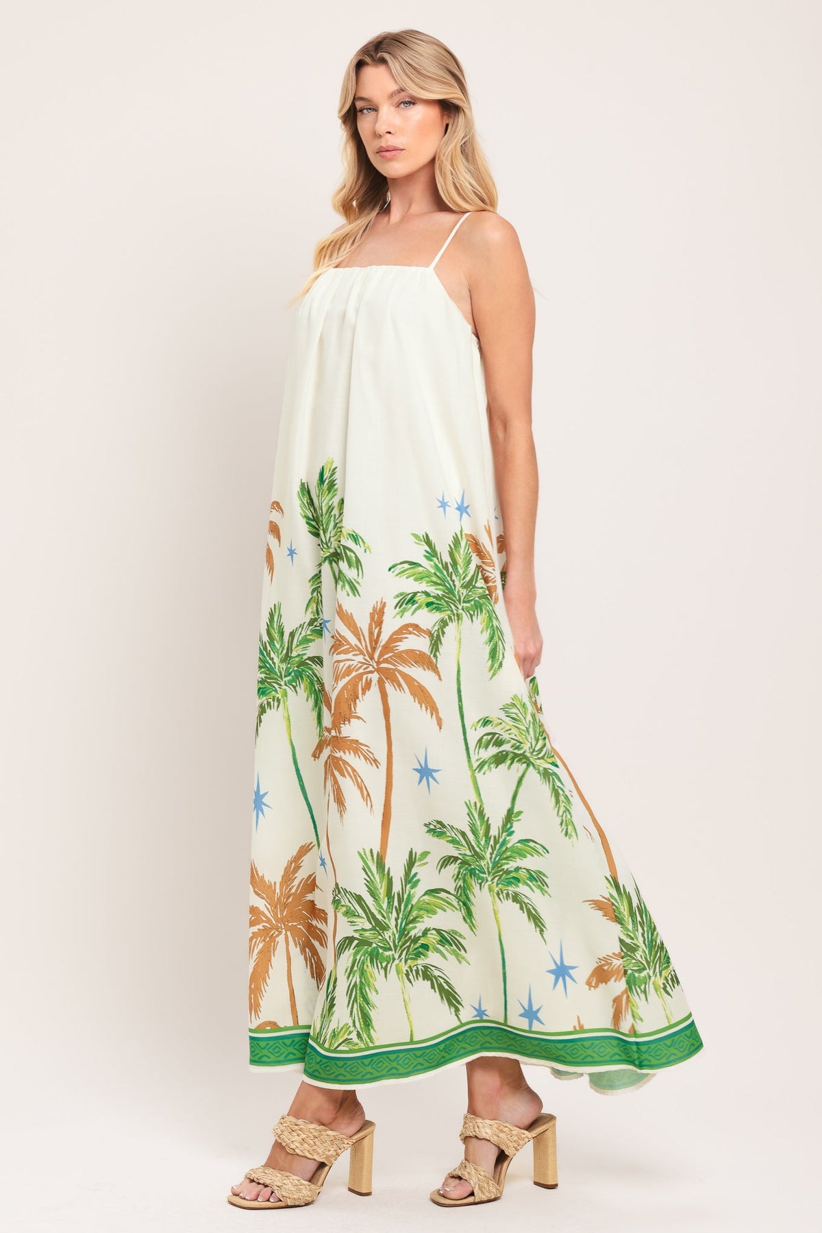 Woman wearing a white dress with palm tree design on a plain background