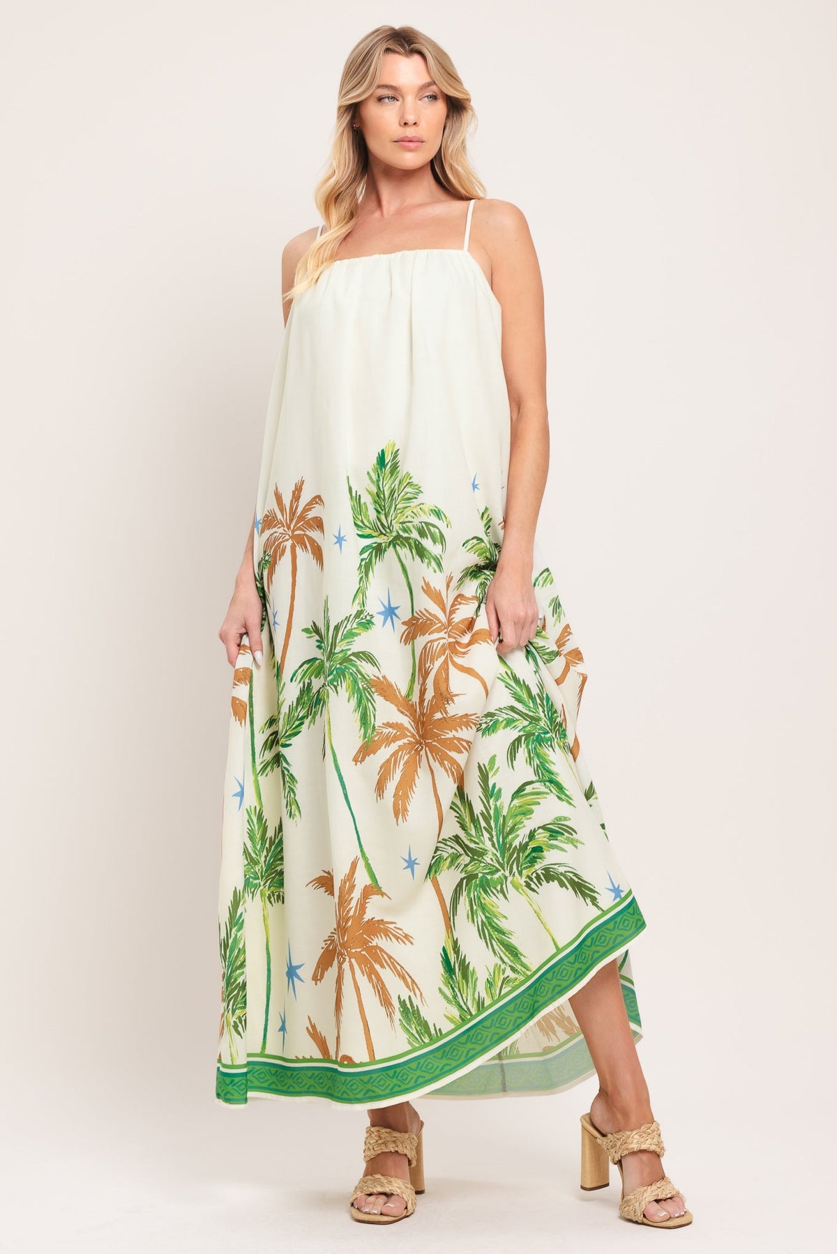Woman wearing a white dress with tropical palm tree pattern on a plain background
