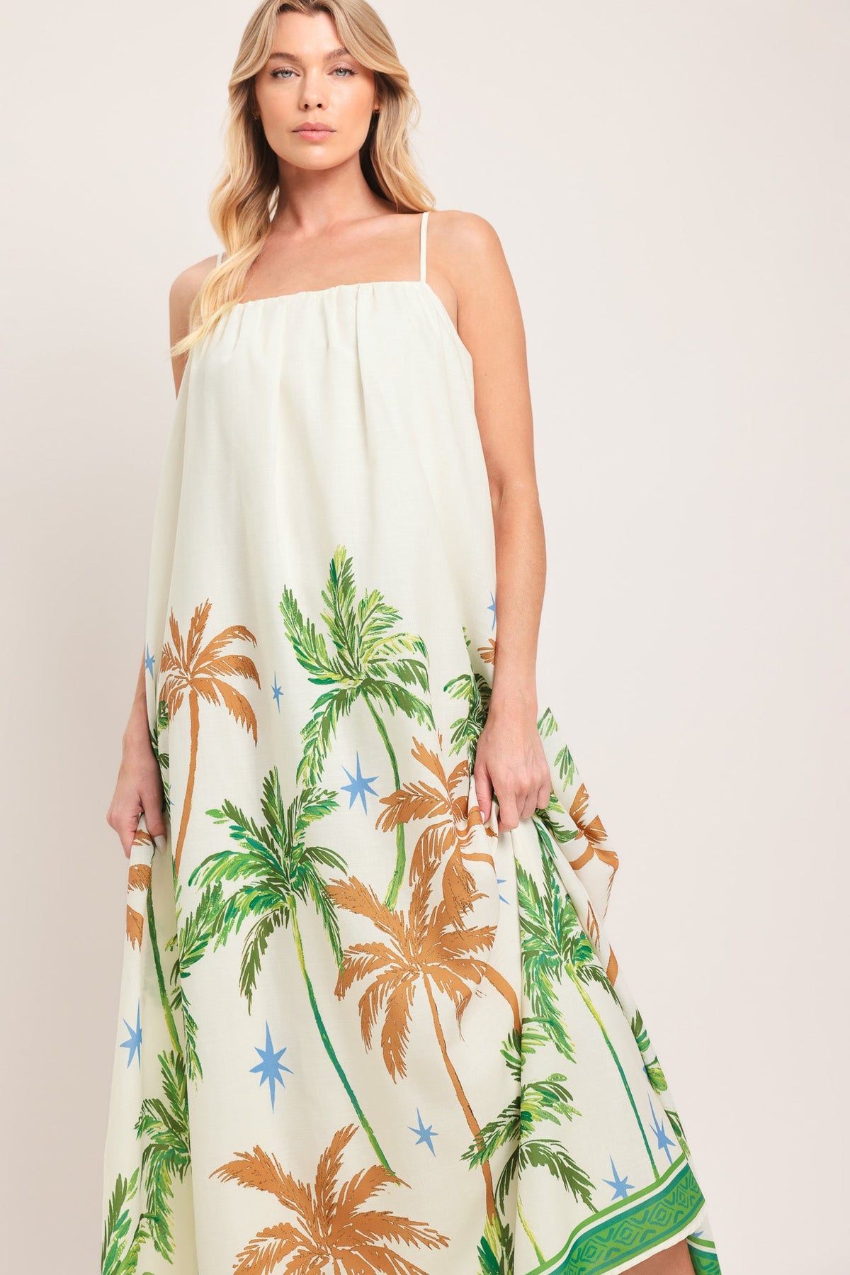 Woman wearing a white dress with palm tree pattern on a plain background