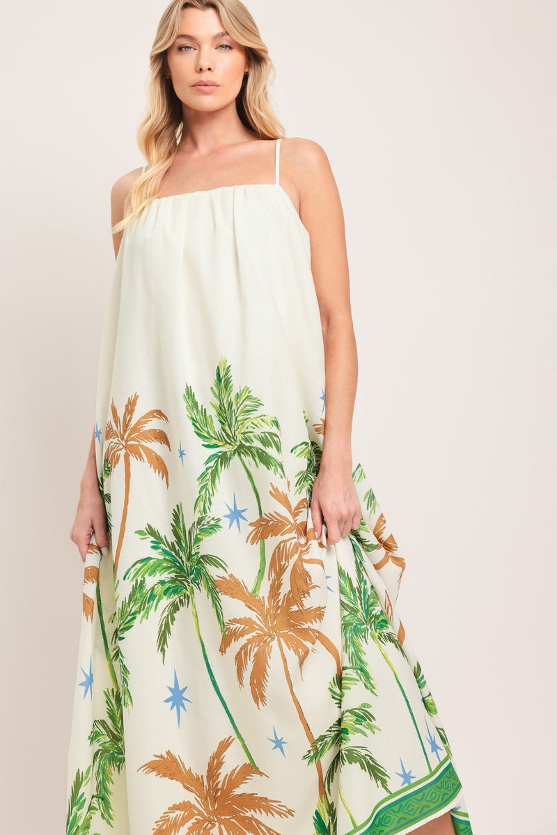Woman wearing a white dress with palm tree pattern on a plain background