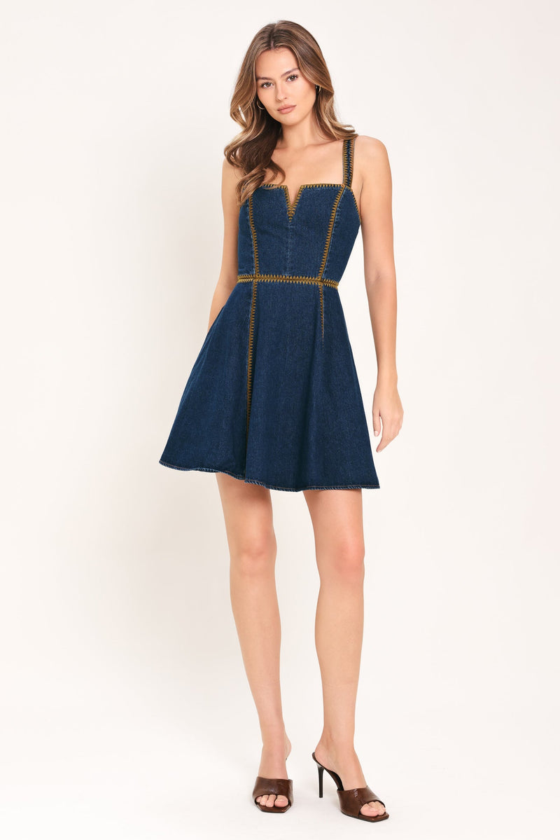 Woman wearing a blue dress with gold accents on a white background