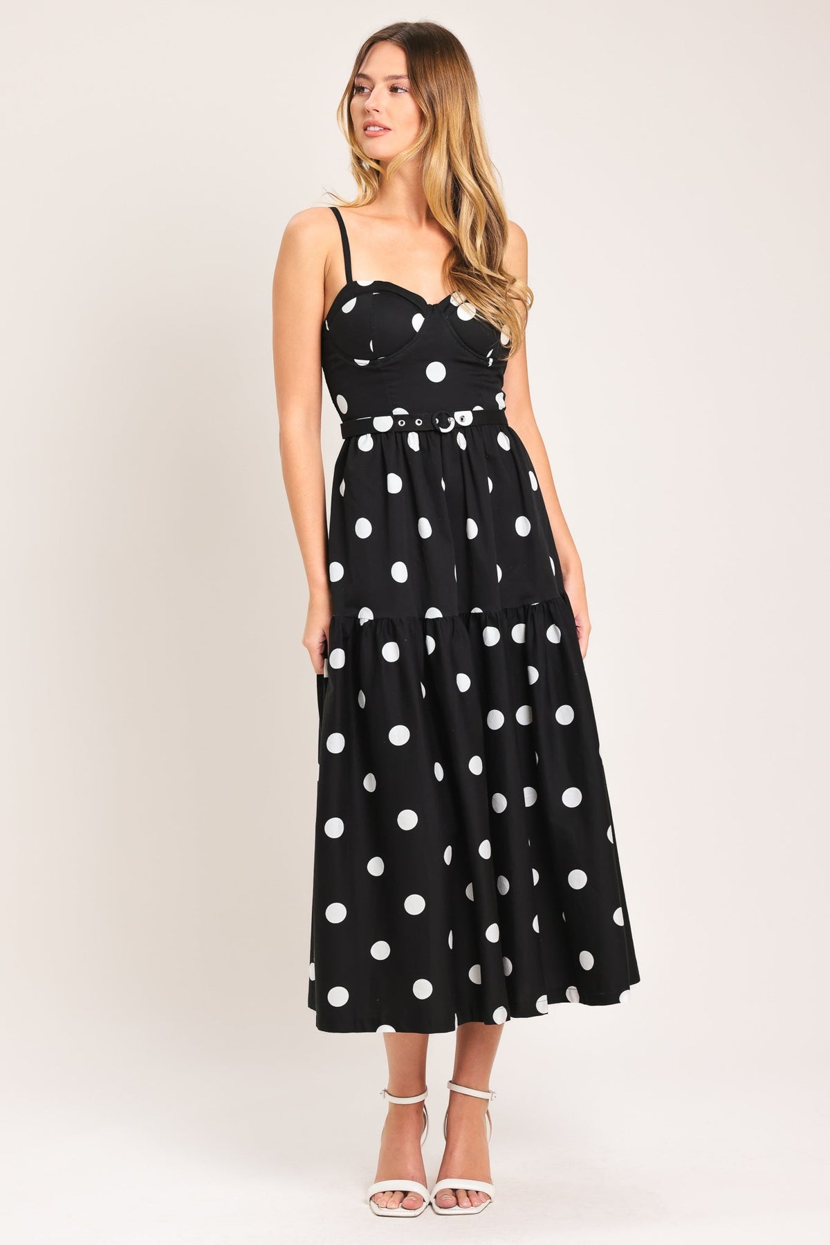 Woman wearing a black dress with white polka dots on a white background