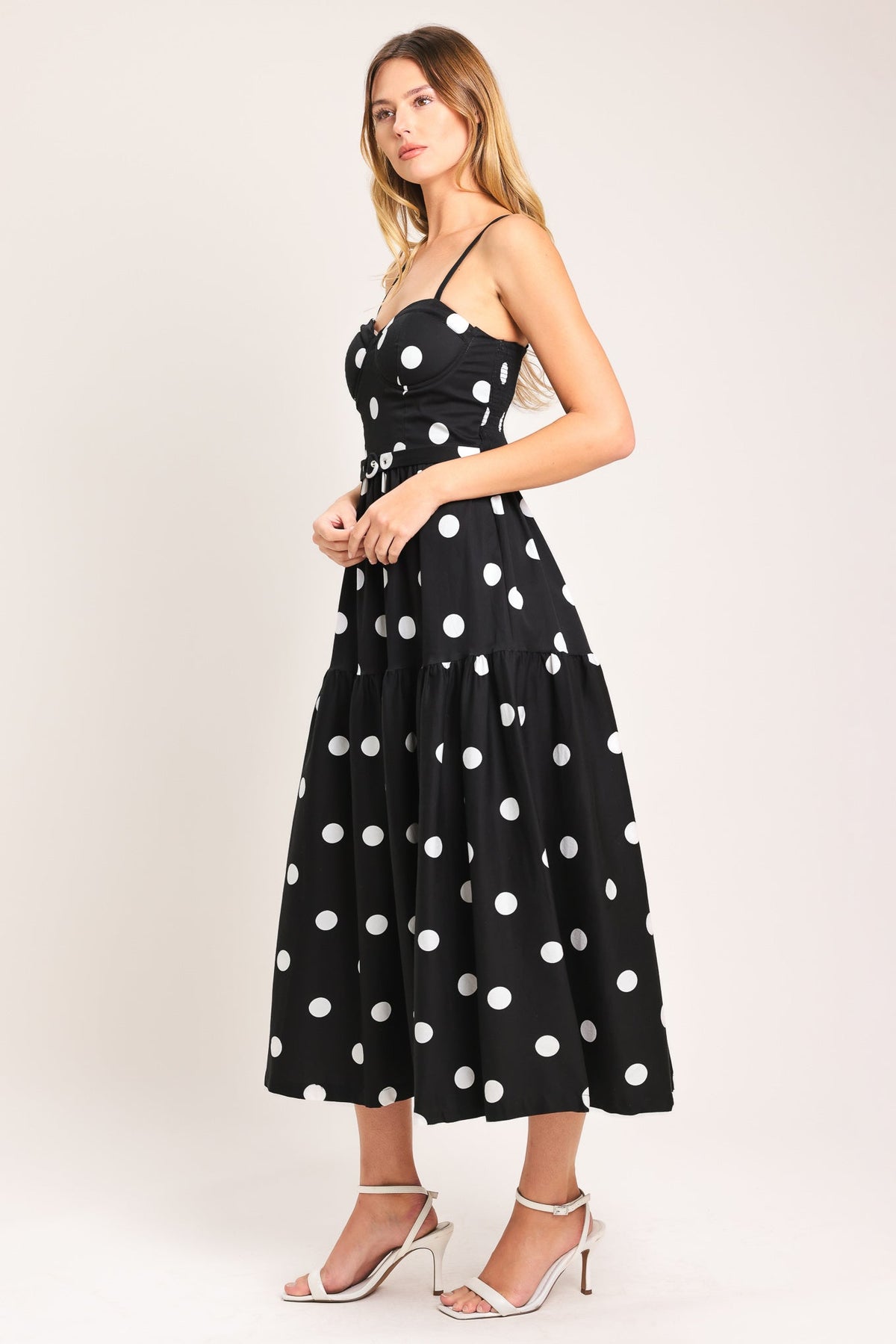 Woman wearing a black dress with white polka dots on a white background