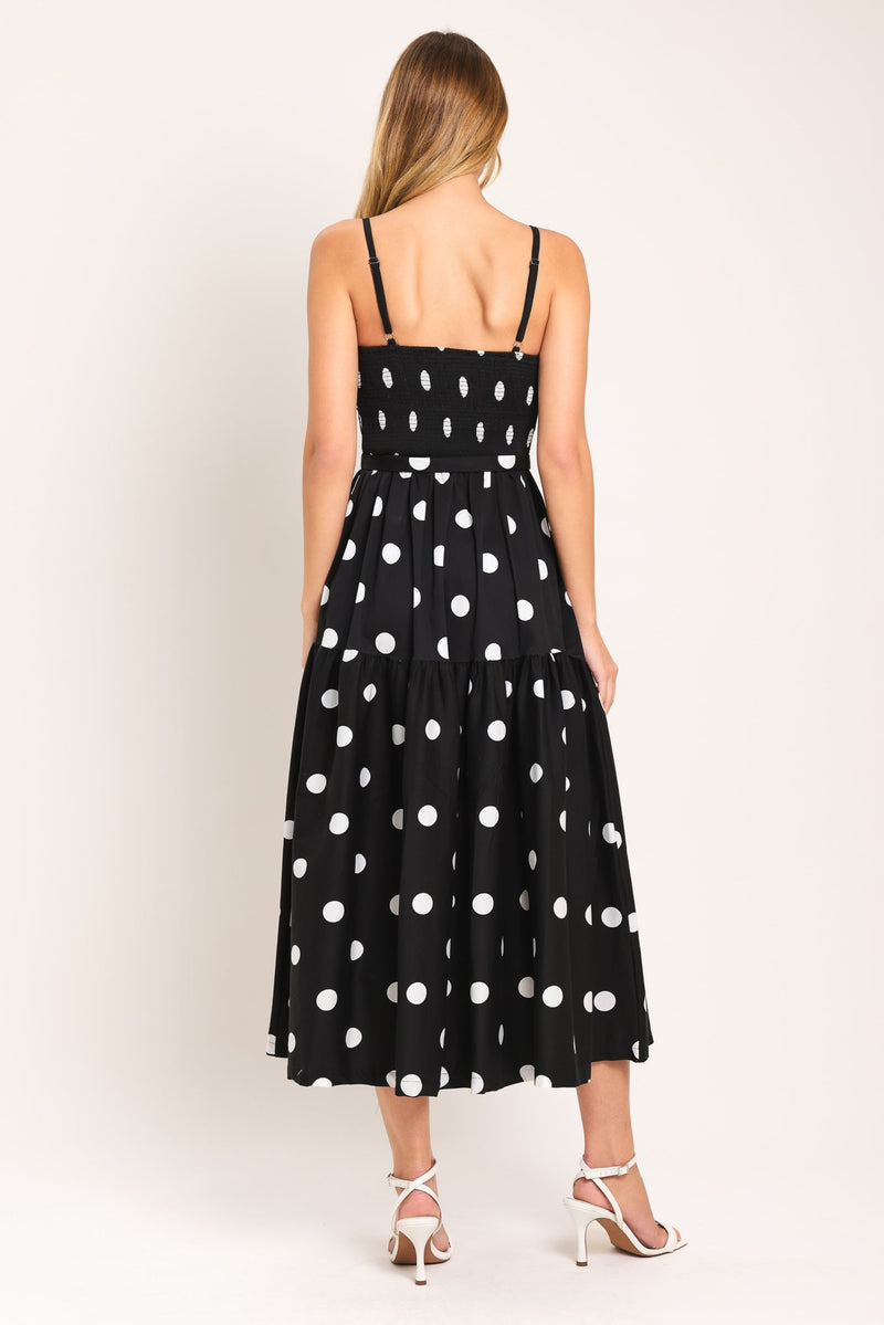 Woman wearing a black dress with white polka dots on a white background