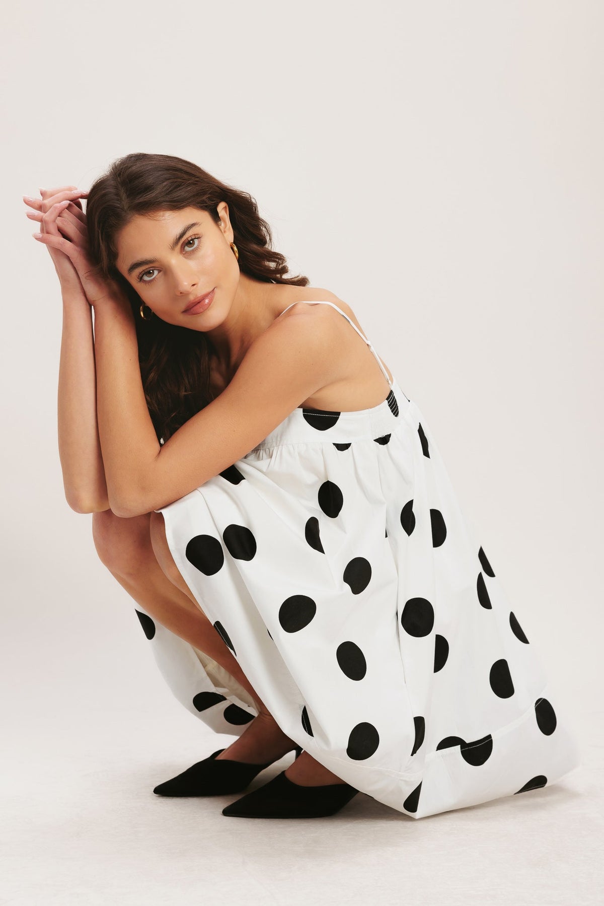 Woman wearing a polka dot dress on a plain background