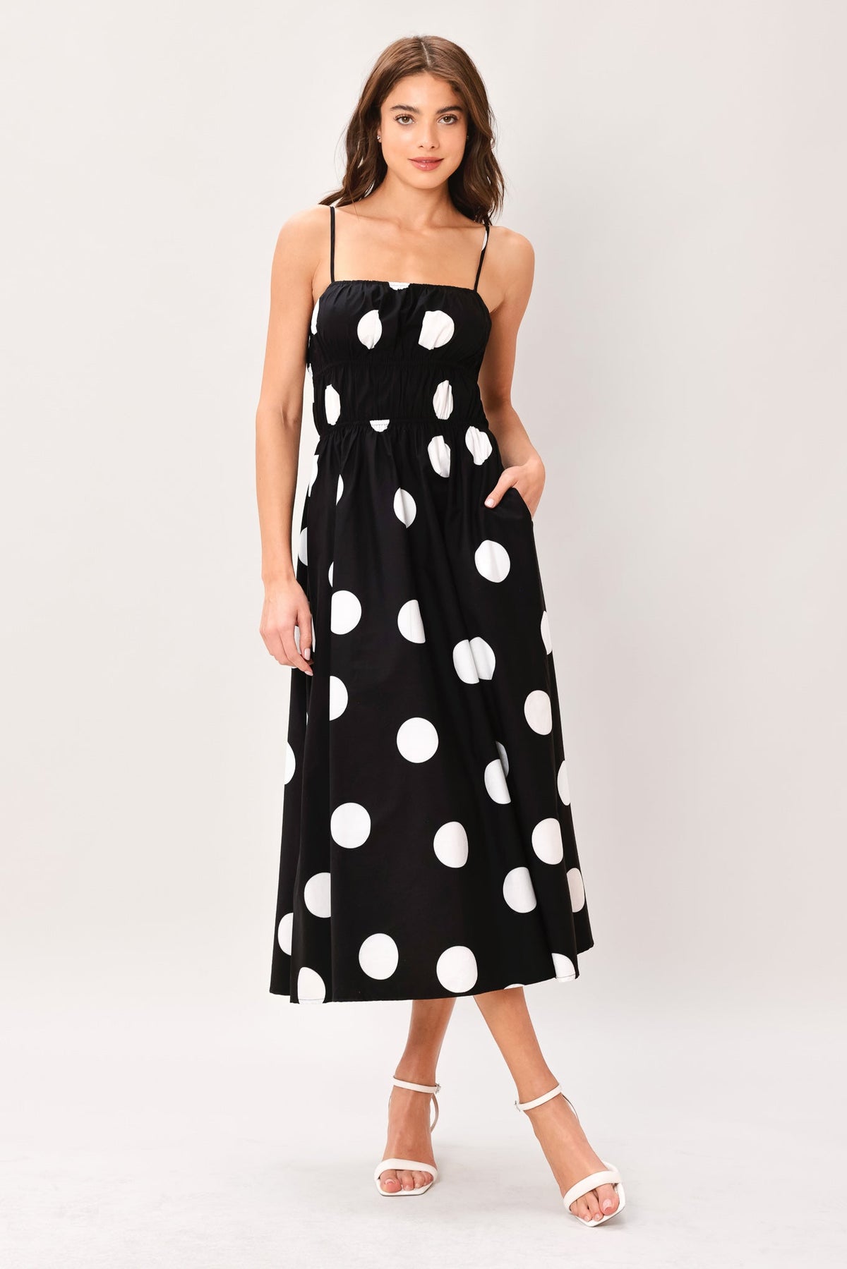 Woman wearing a black dress with white polka dots on a white background