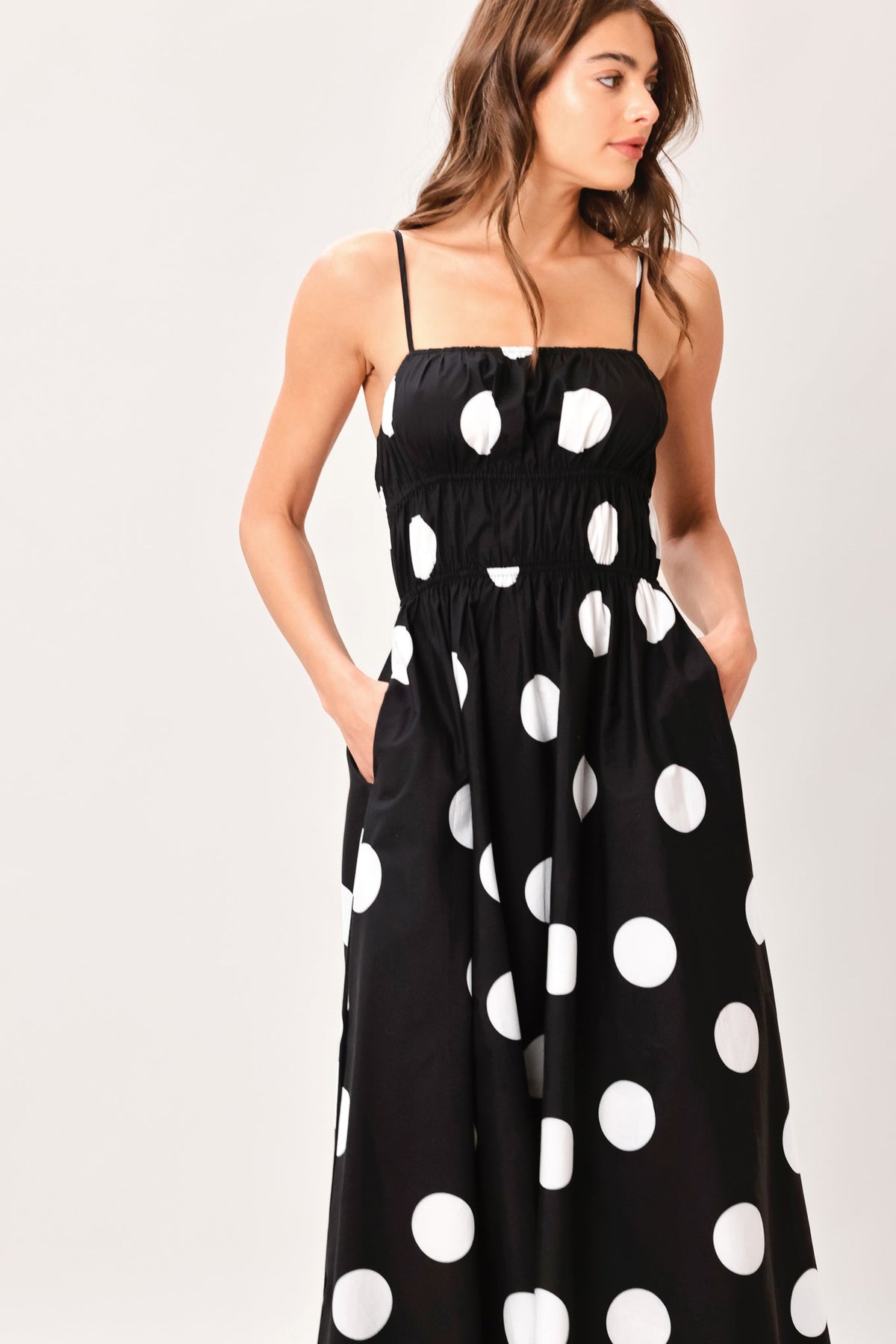 Woman wearing a black dress with white polka dots on a plain background