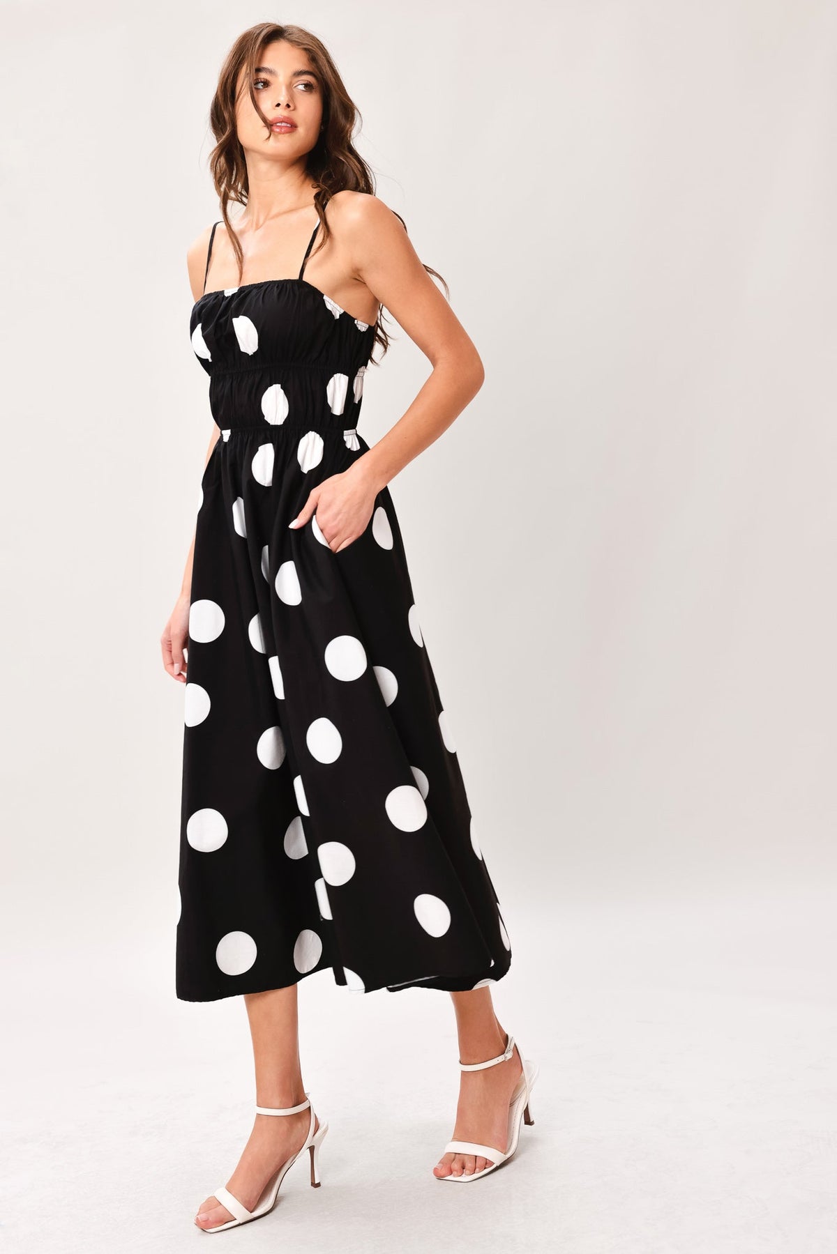 Woman wearing a black dress with white polka dots on a white background