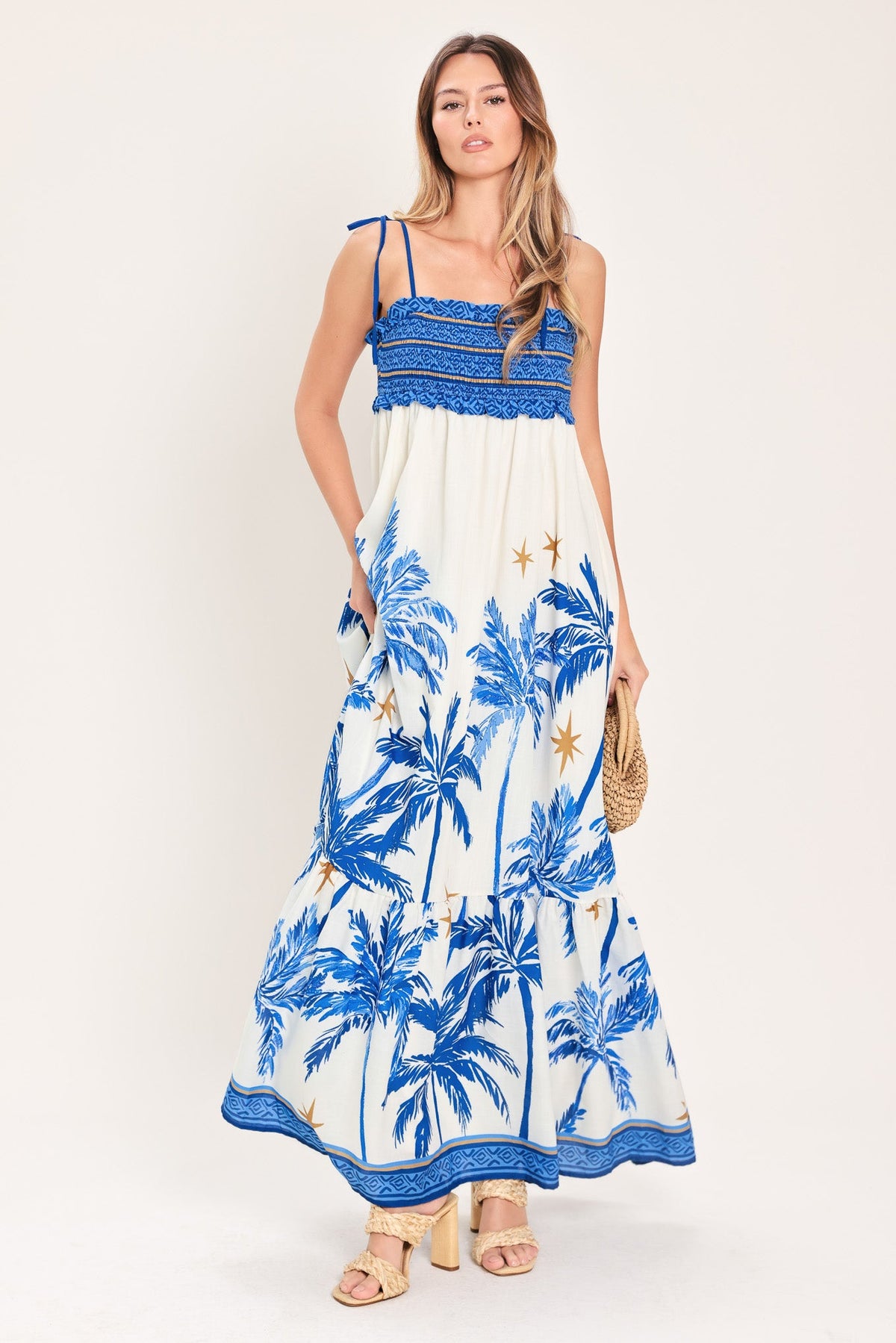 Woman wearing a blue and white palm tree patterned dress on a white background