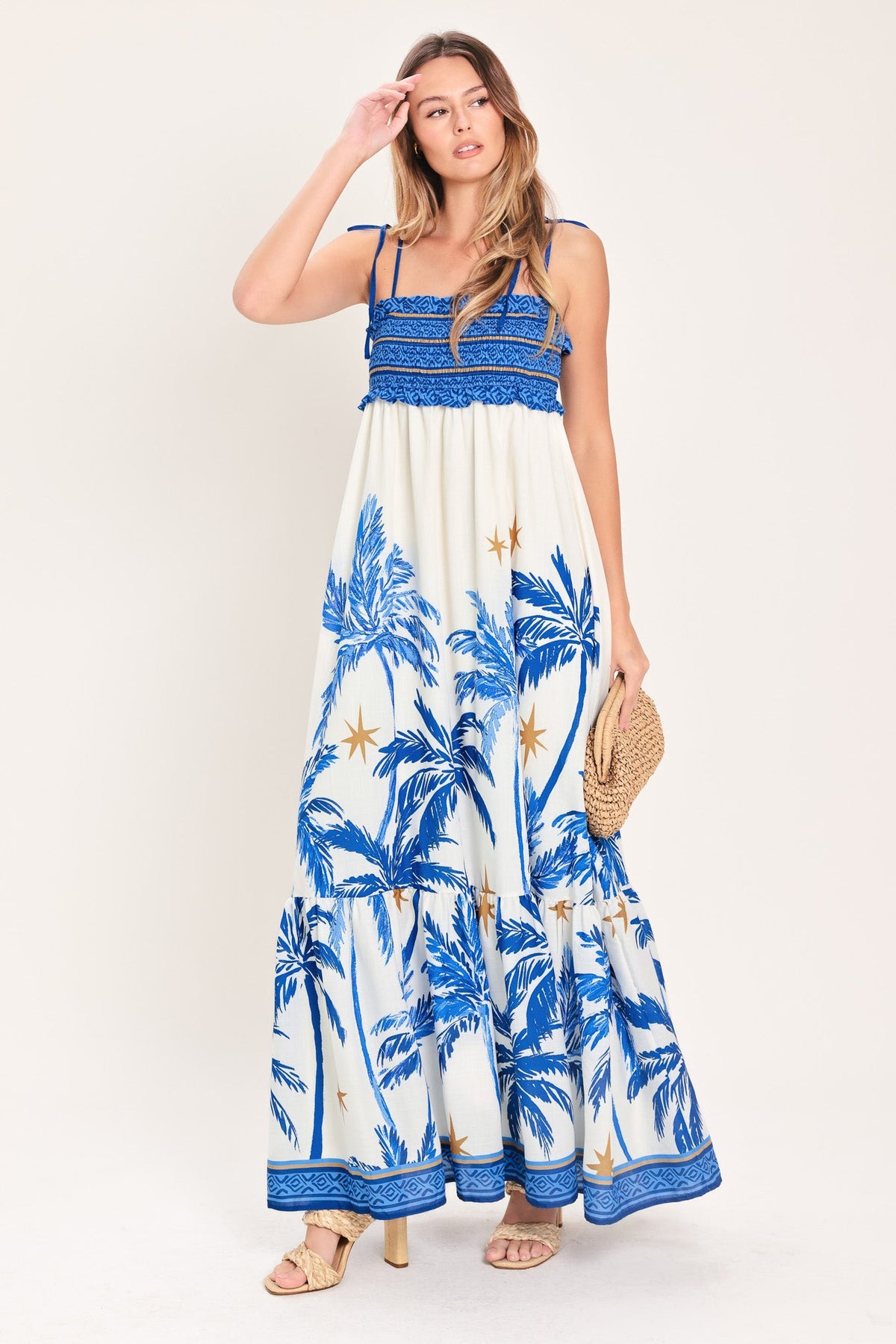 Woman wearing a blue and white palm tree patterned dress on a white background