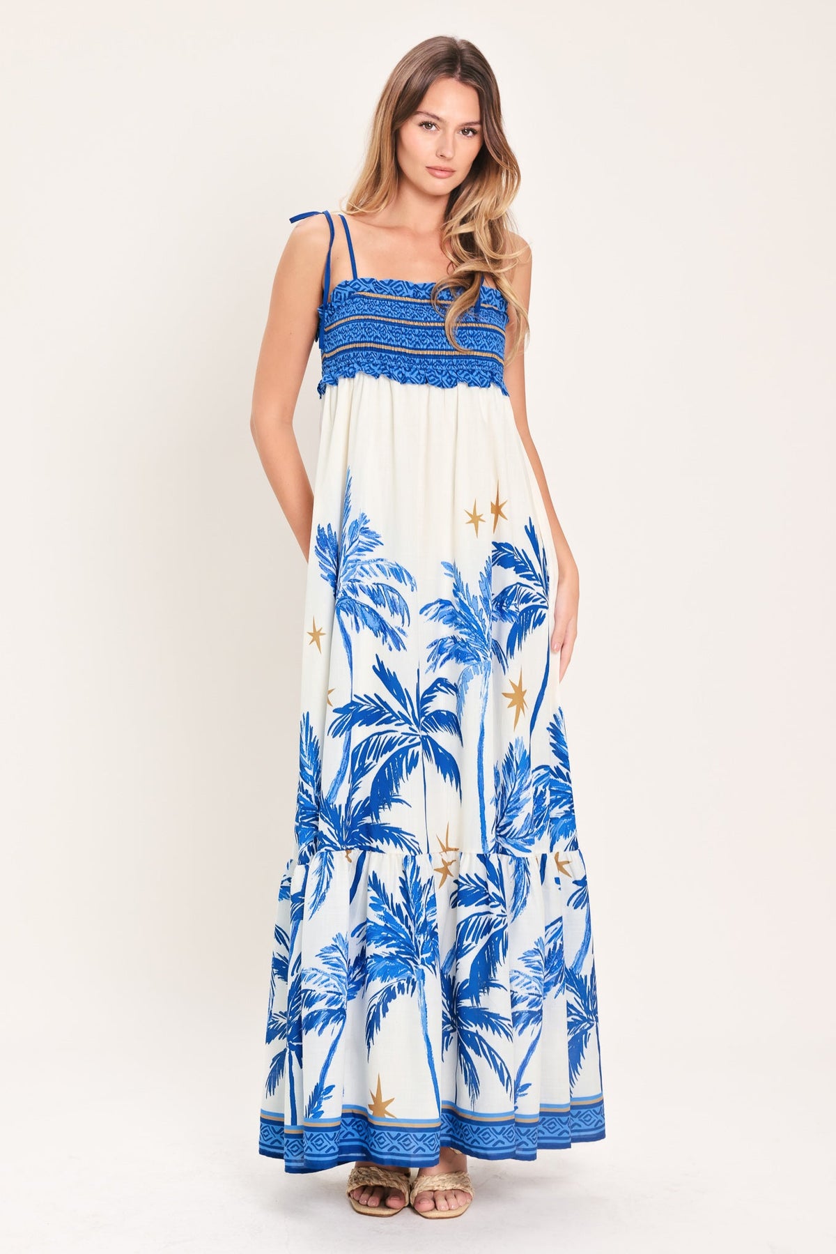Woman wearing a blue and white dress with palm tree pattern on a white background