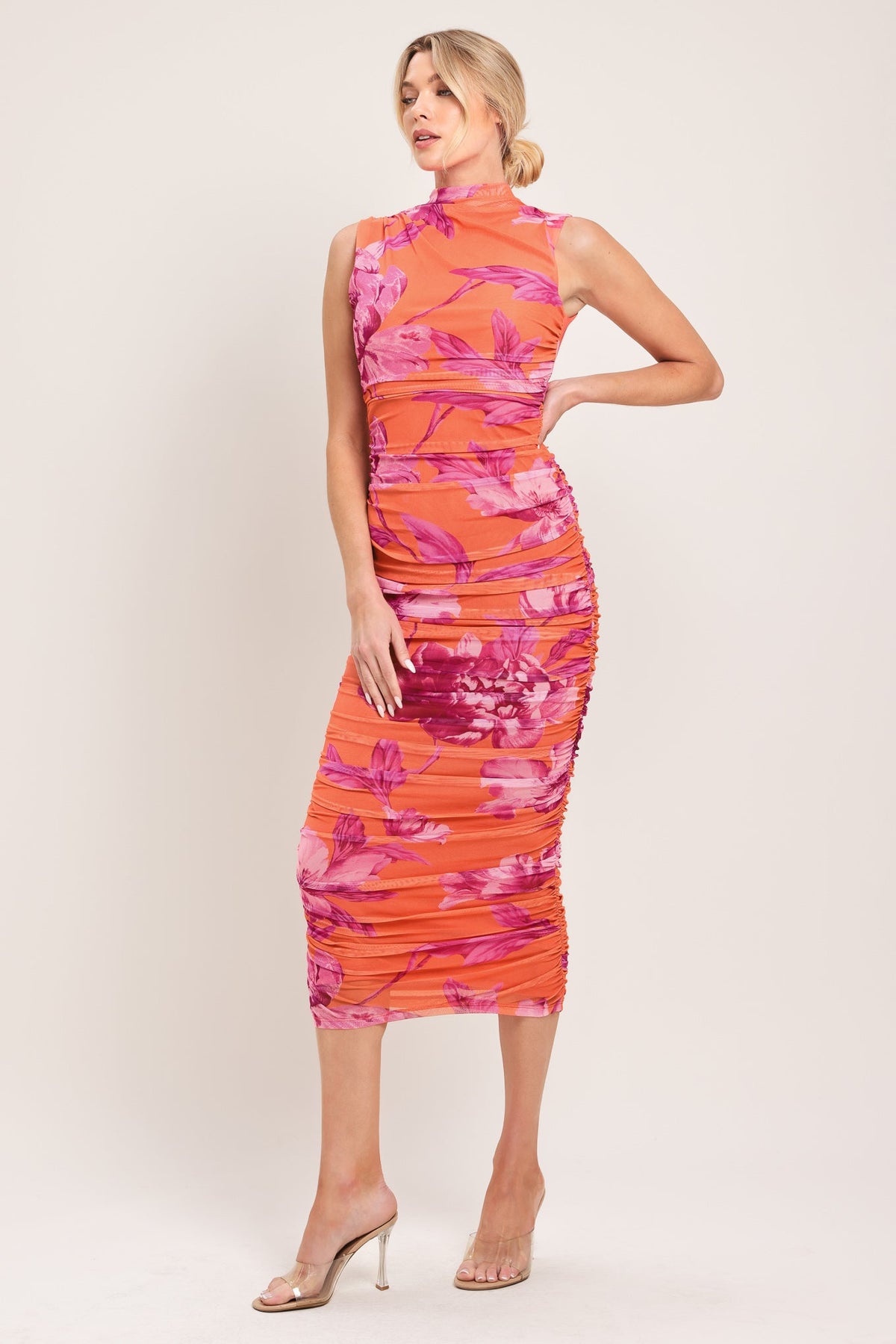 Woman wearing a sleeveless dress with pink floral pattern on a white background
