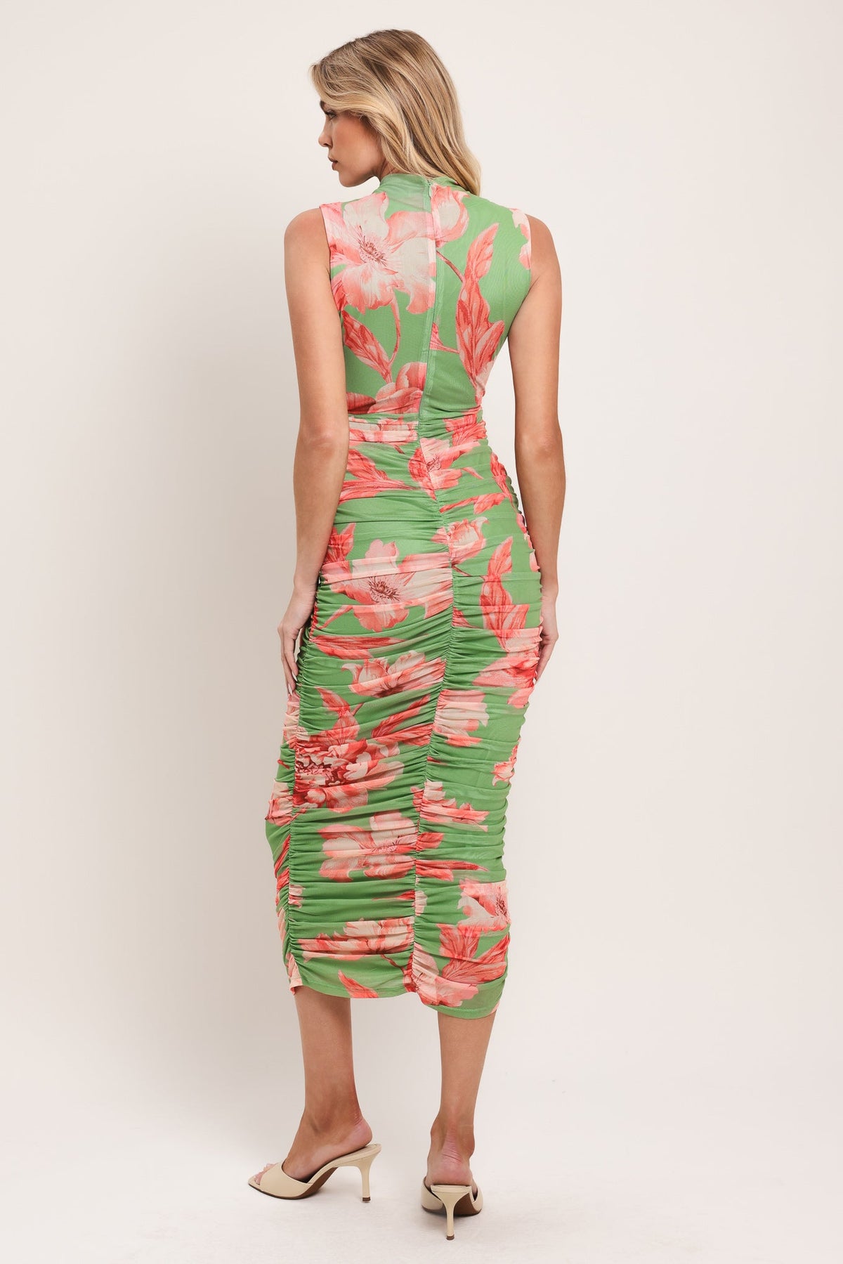 Woman wearing a green and pink floral dress on a white background