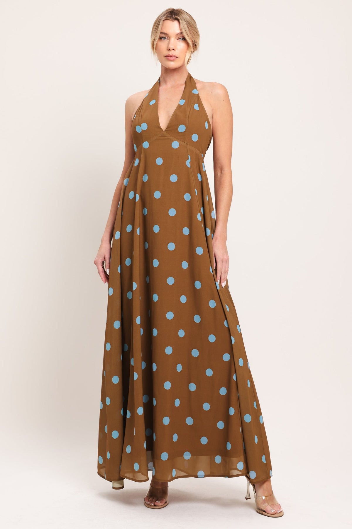 Woman wearing a brown halter neck dress with blue polka dots on a beige background