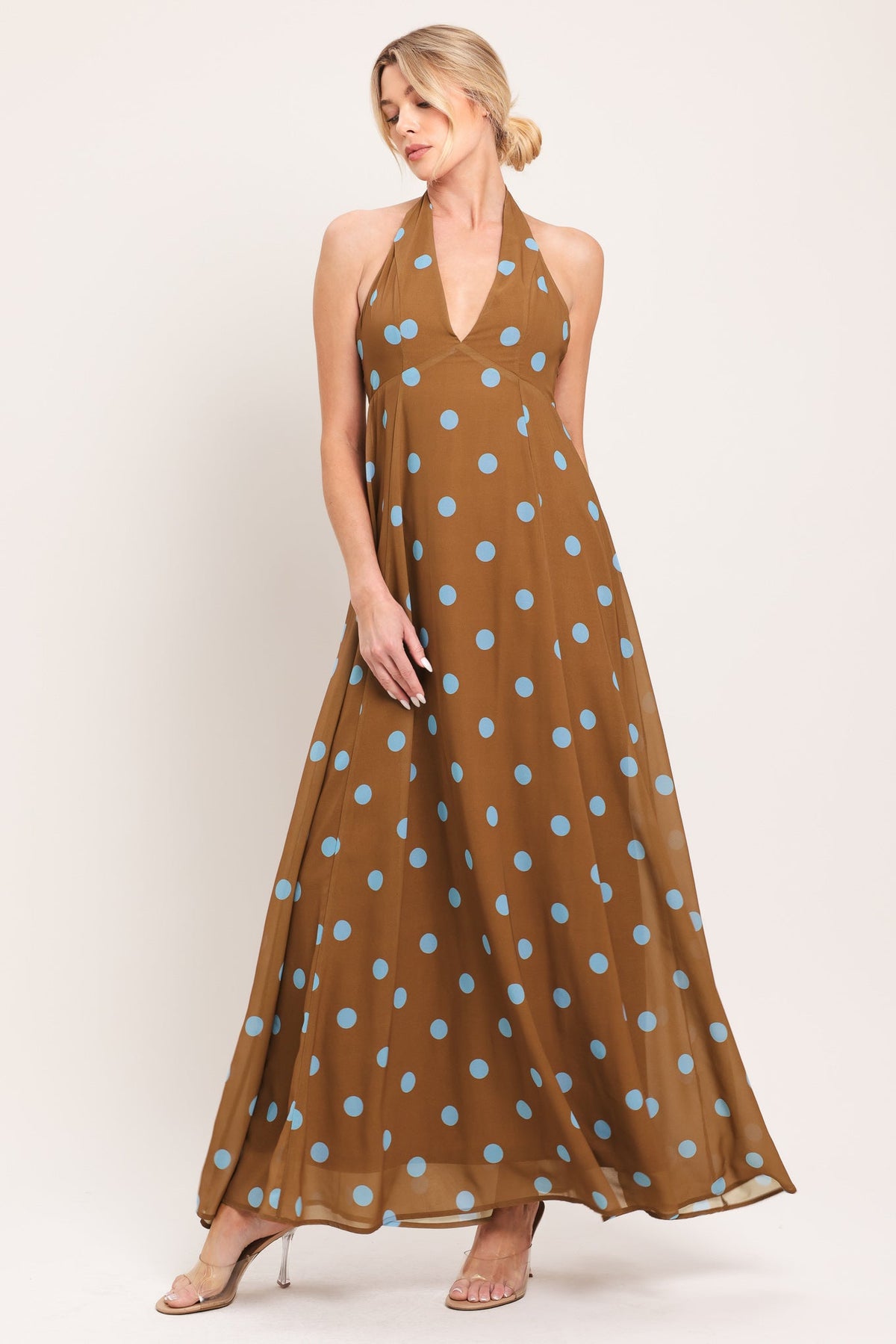 Woman wearing a brown dress with blue polka dots on a white background