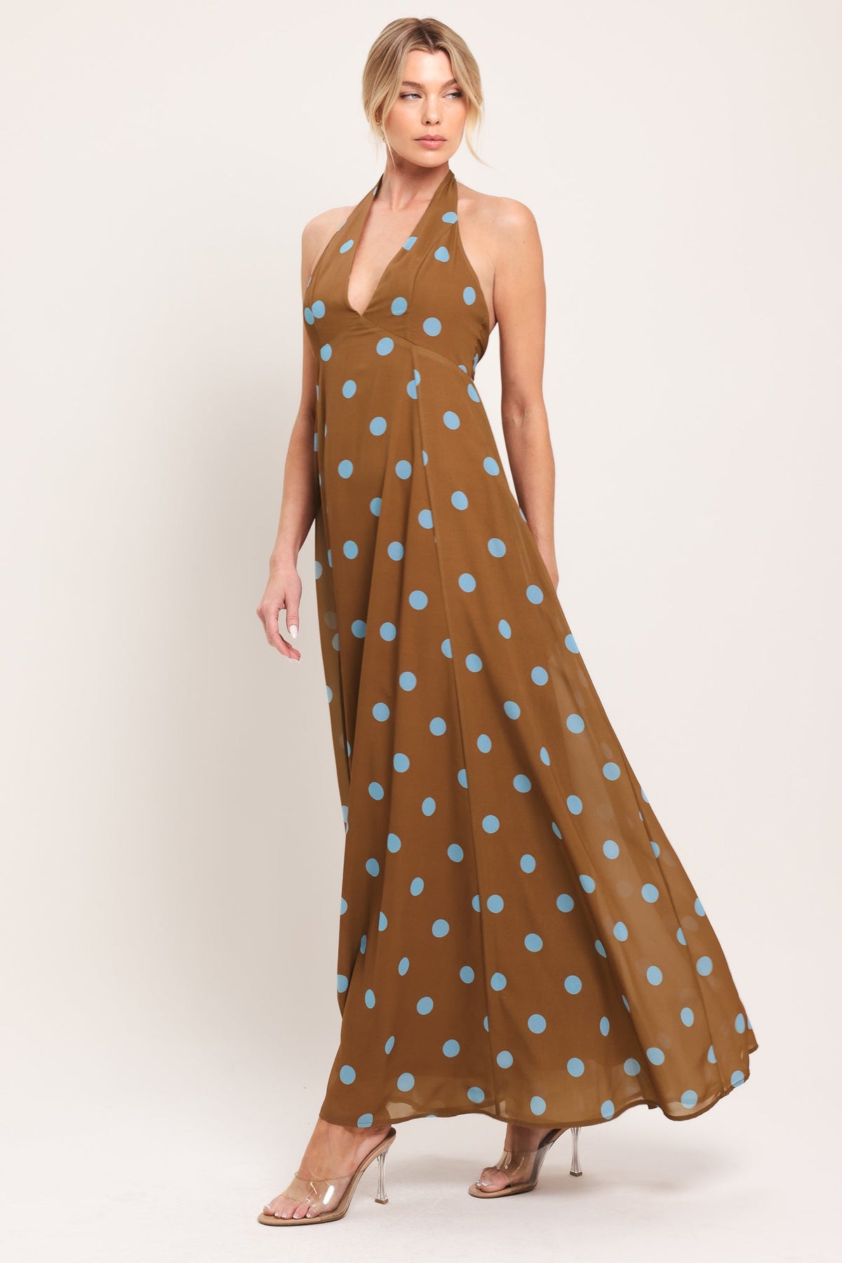 Woman wearing a brown dress with blue polka dots on a white background