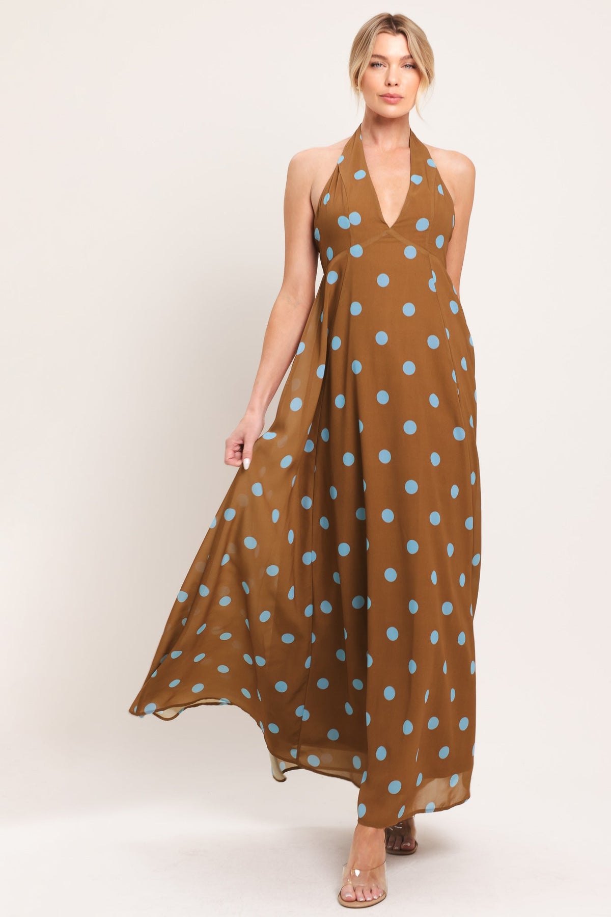 Woman wearing a brown dress with blue polka dots on a white background