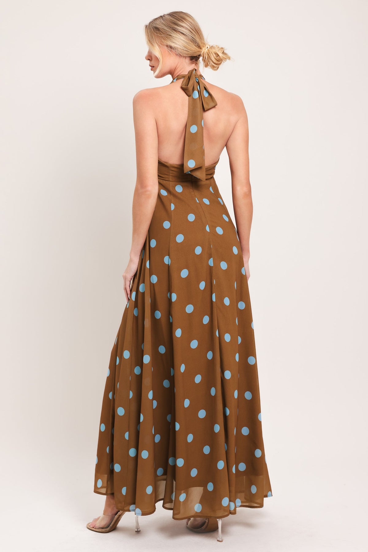 Woman wearing a brown dress with blue polka dots on a white background