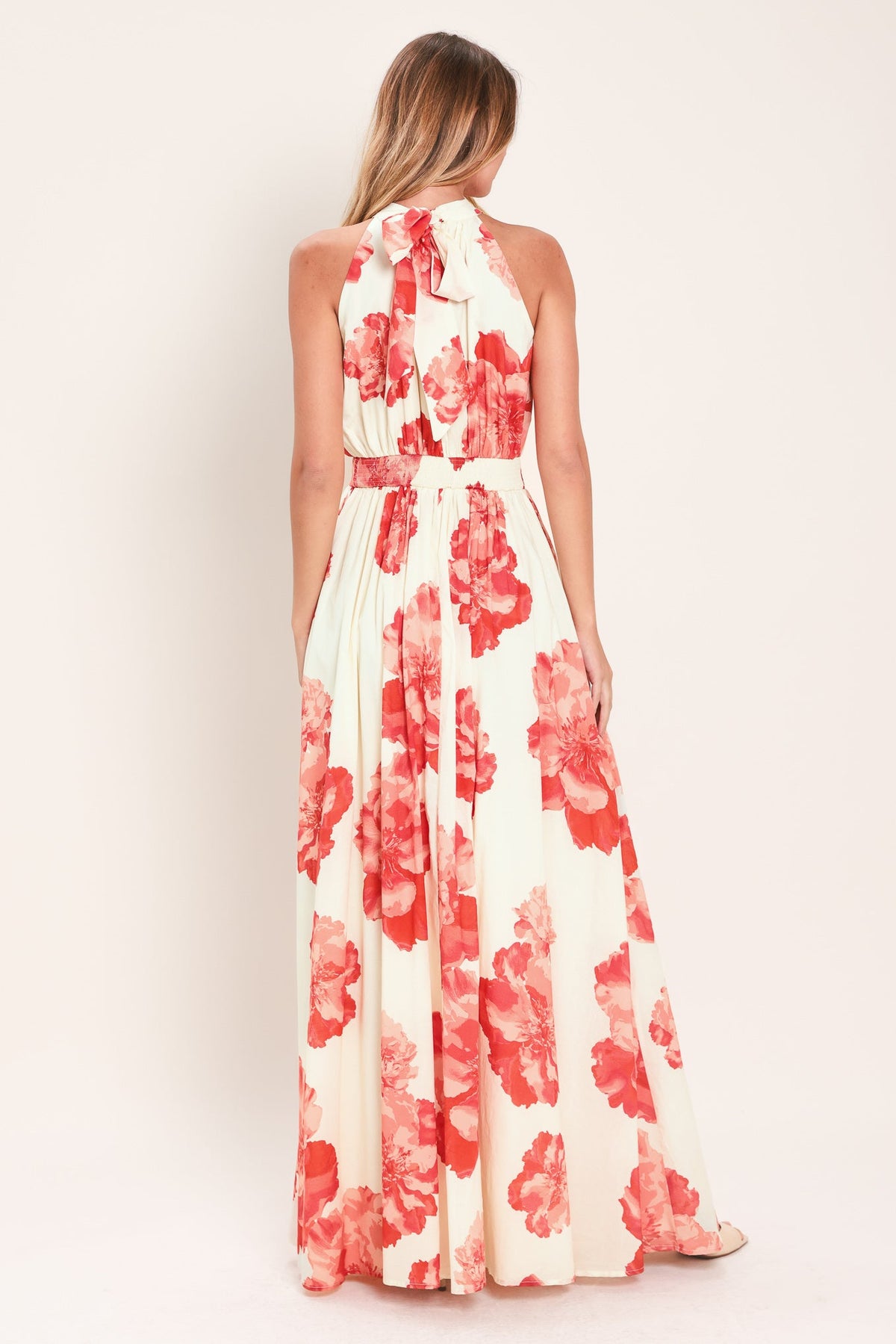 Woman wearing a floral maxi dress with red flowers on a white background