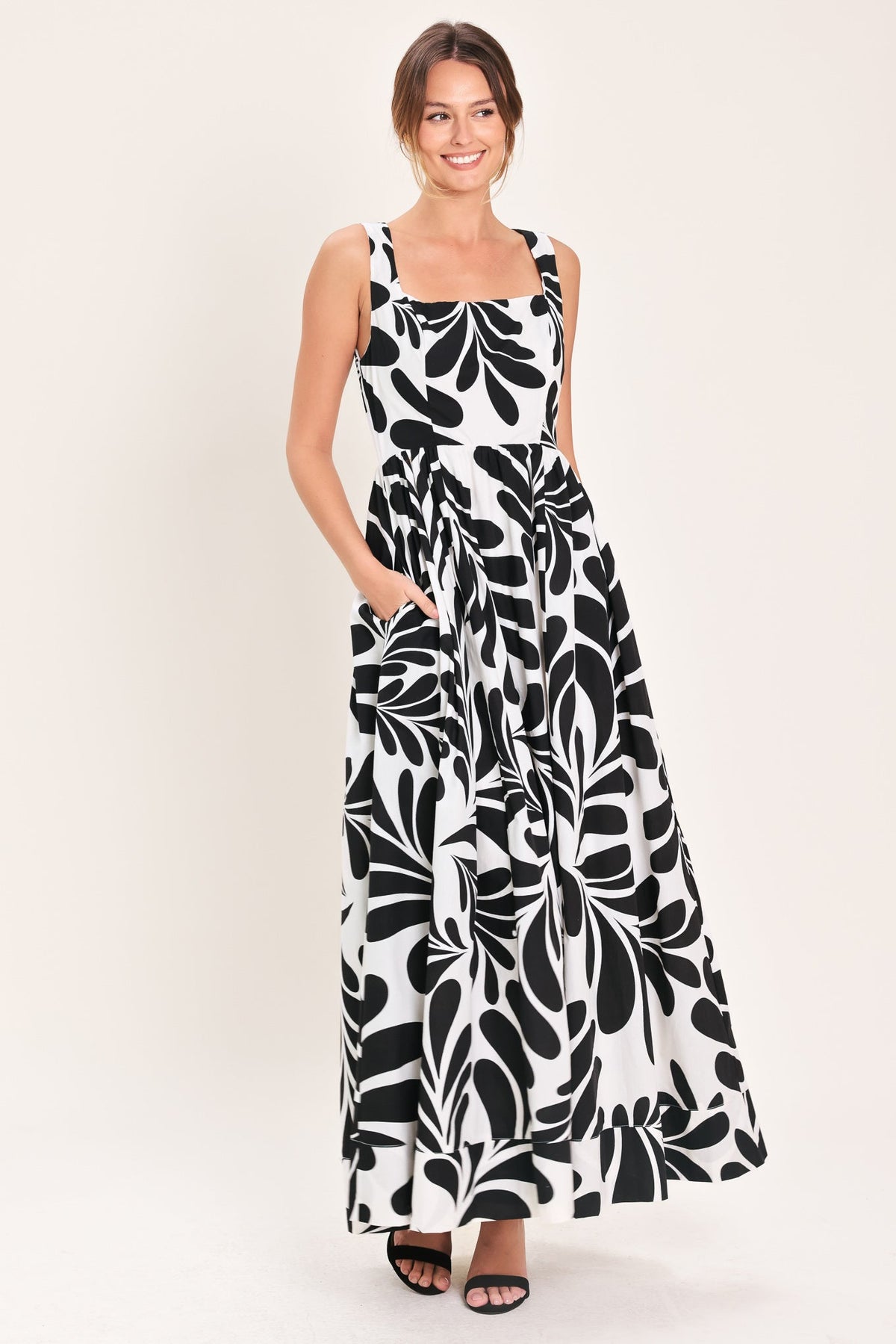Woman wearing a black and white floral patterned dress on a plain background