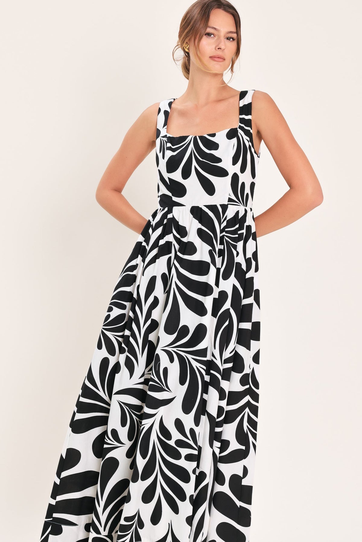 Woman wearing a black and white patterned dress against a plain background