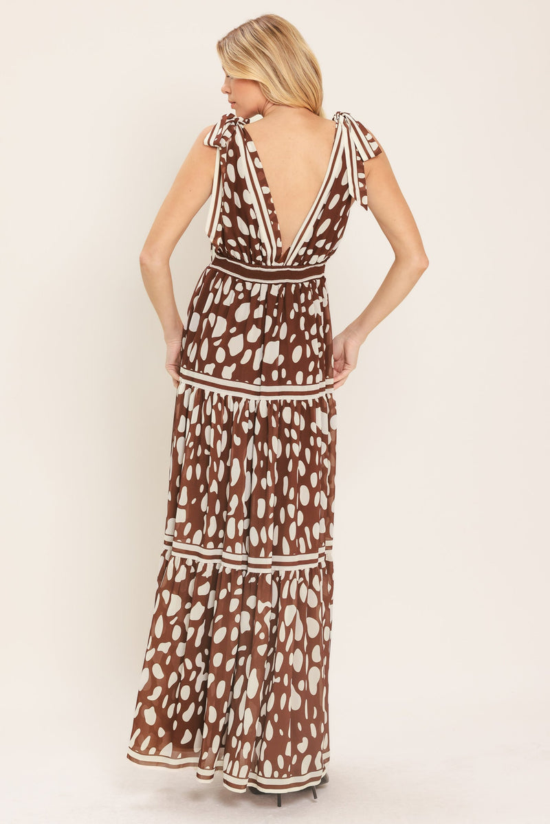 Woman wearing a brown and white patterned dress against a plain background