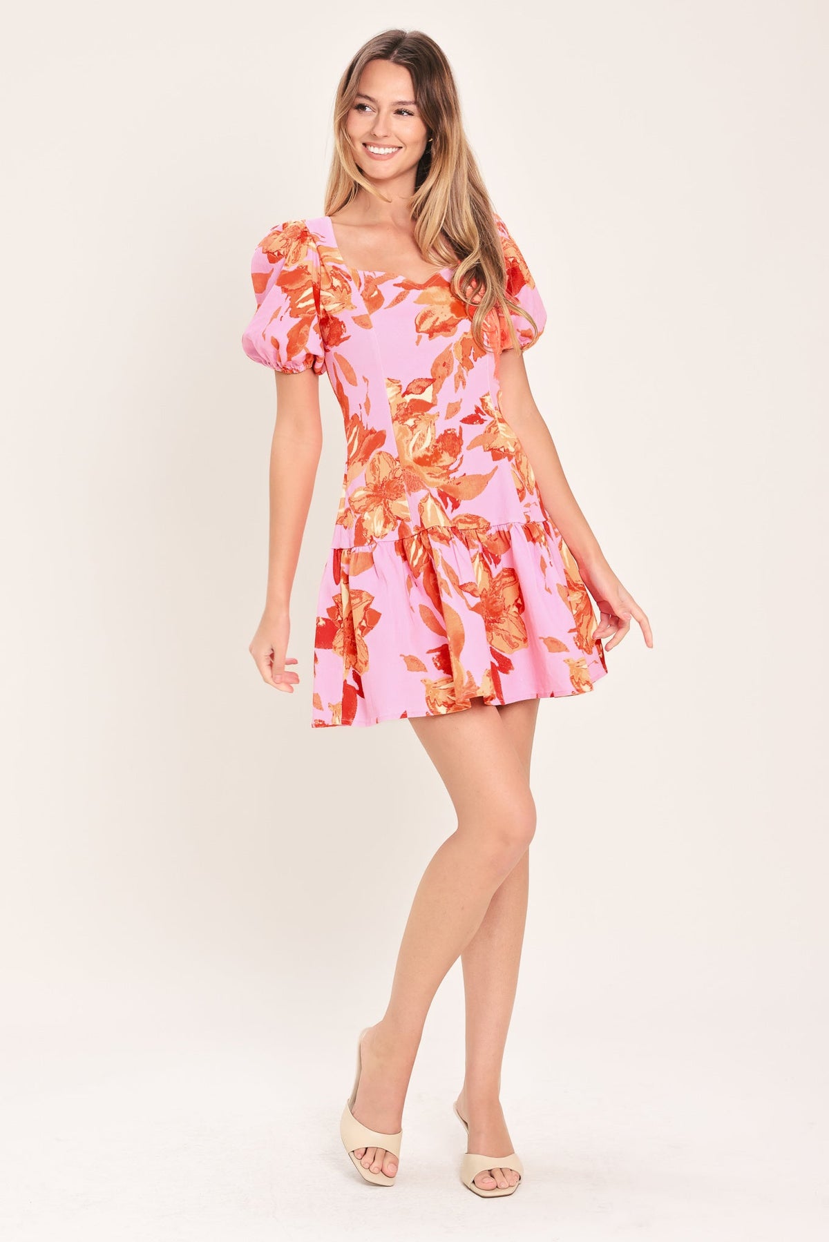 Woman wearing a pink floral dress on a plain background