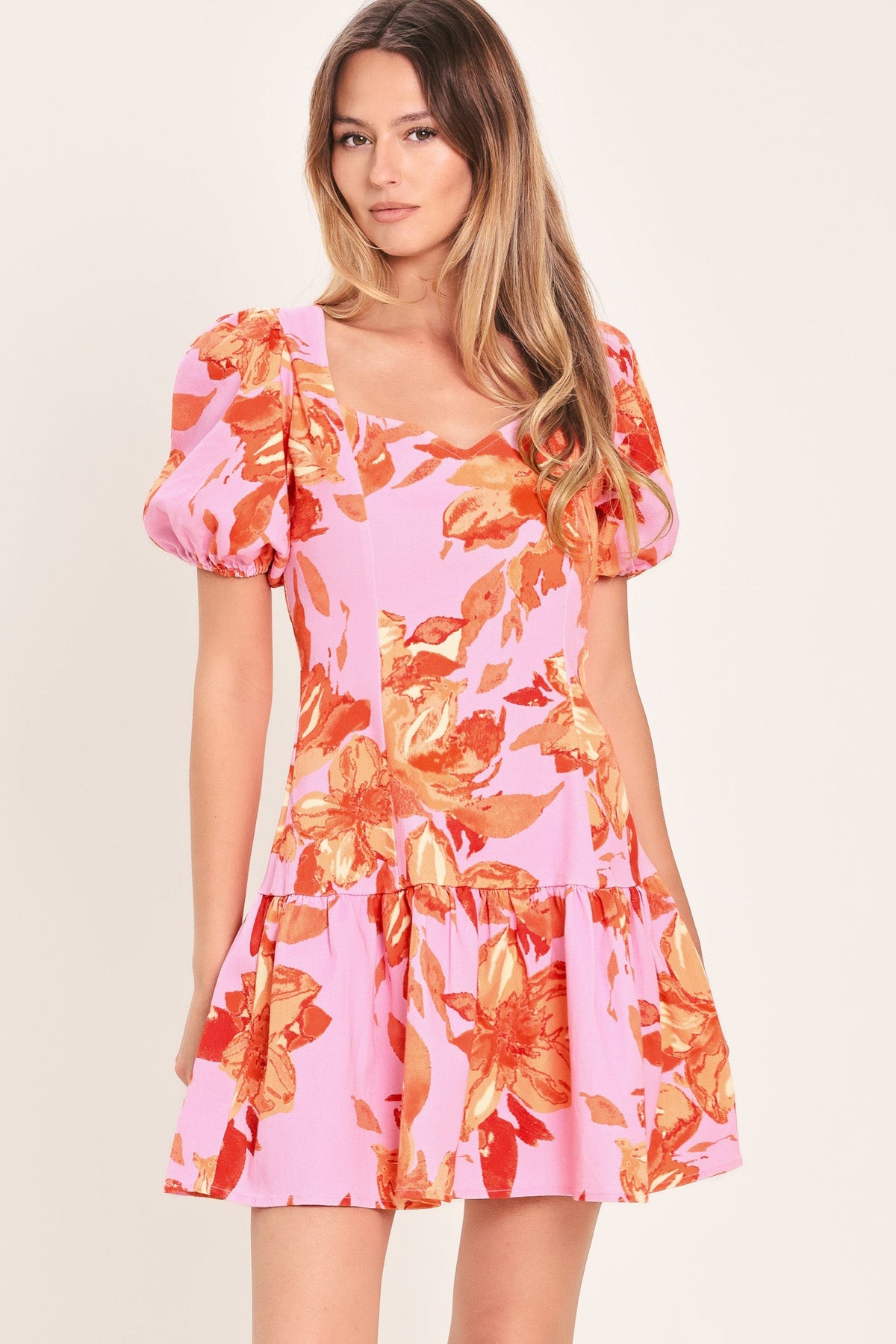Woman wearing a pink floral dress on a plain background