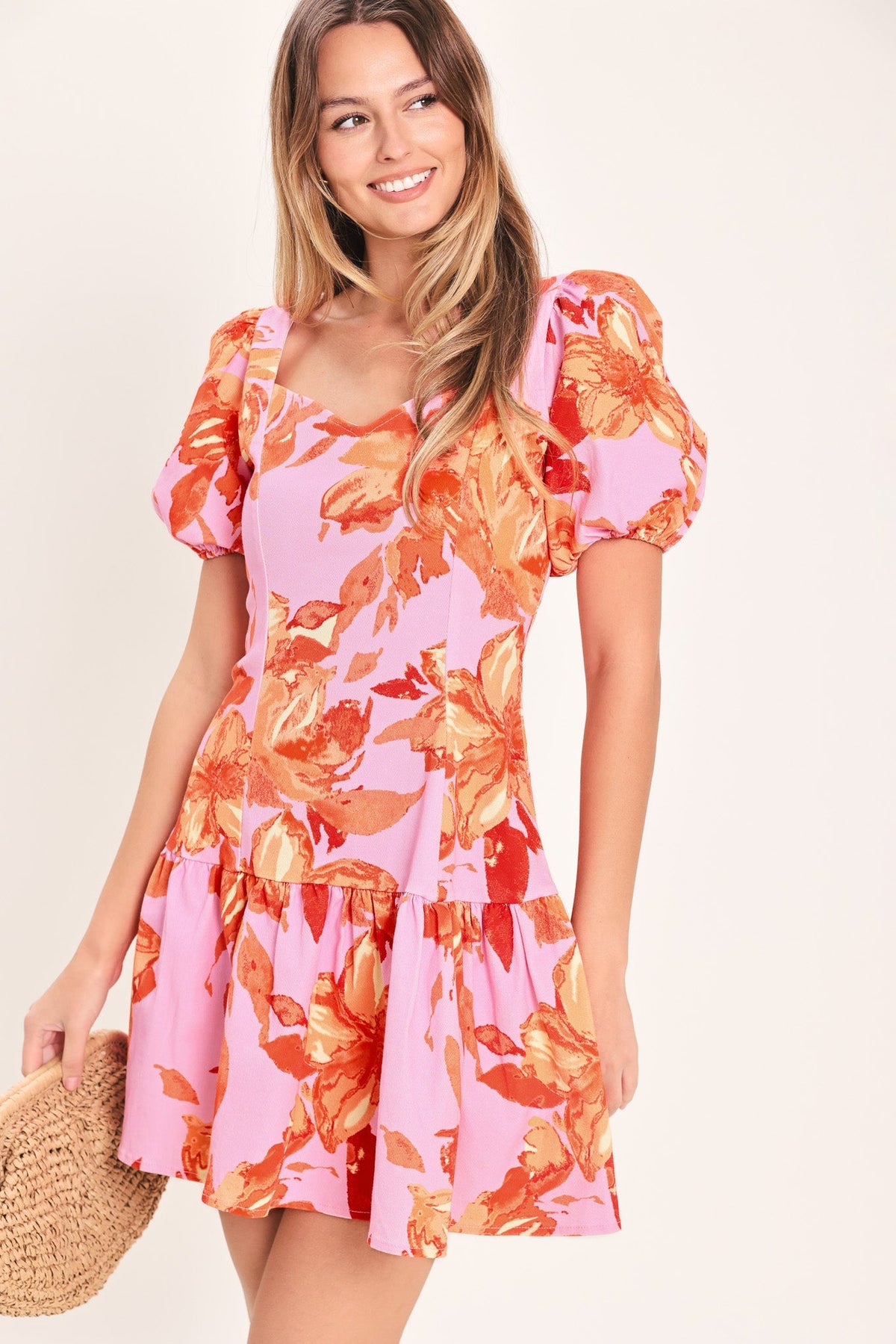 Woman wearing a pink floral dress with orange flowers on a beige background