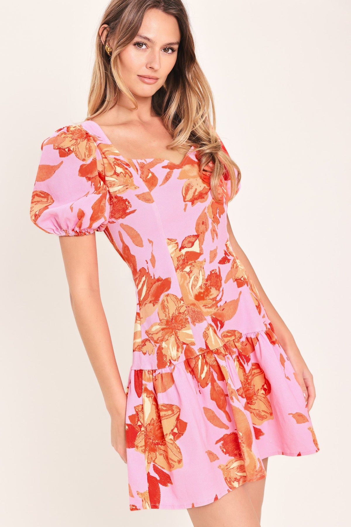 Woman wearing a pink floral dress against a beige background