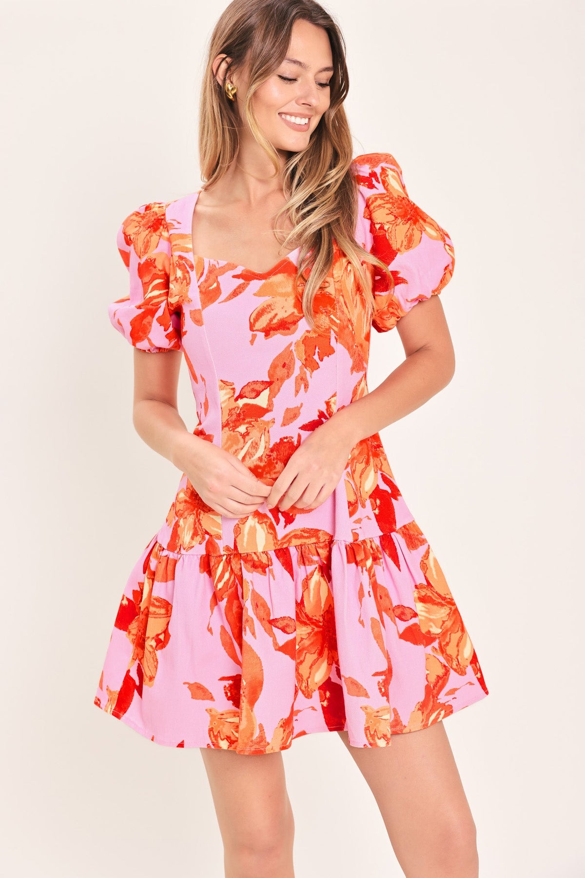 Woman wearing a pink and orange floral dress with puff sleeves on a white background