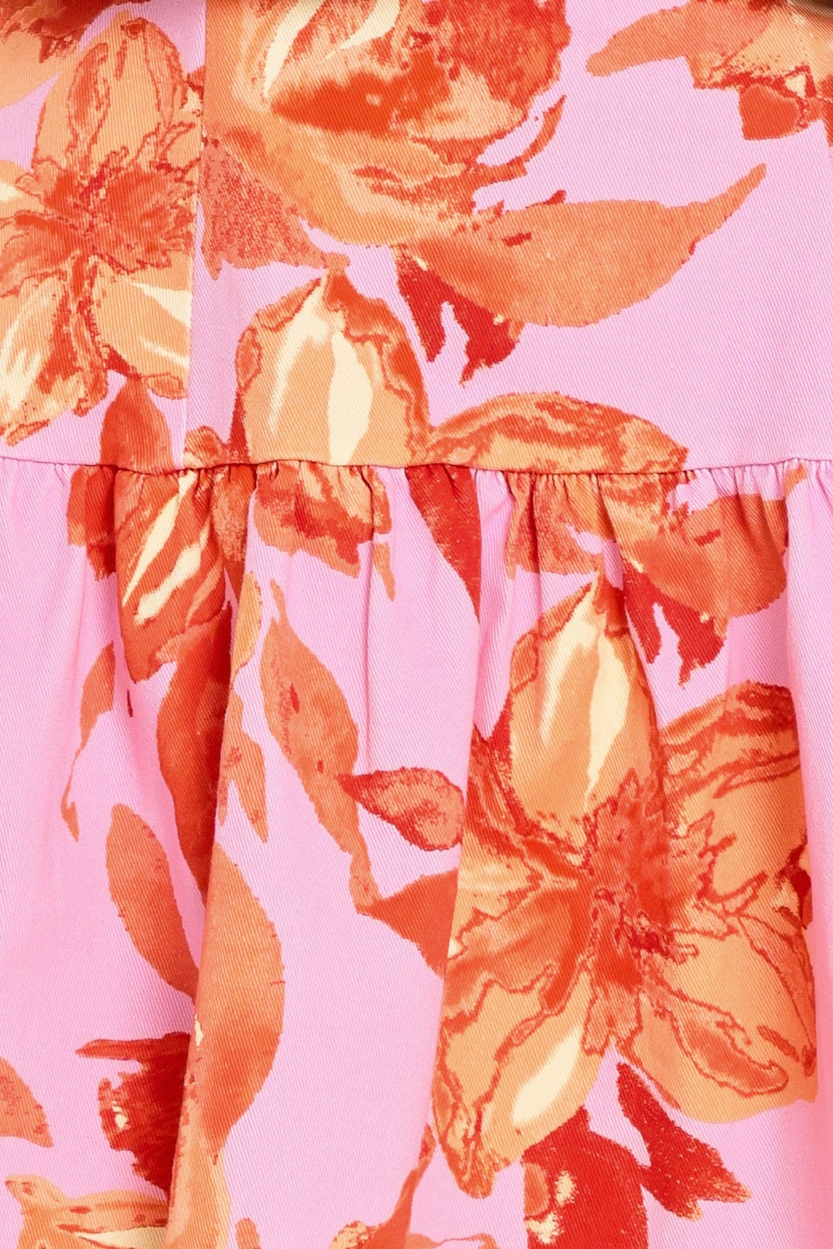 Close-up of a pink fabric with large orange floral patterns