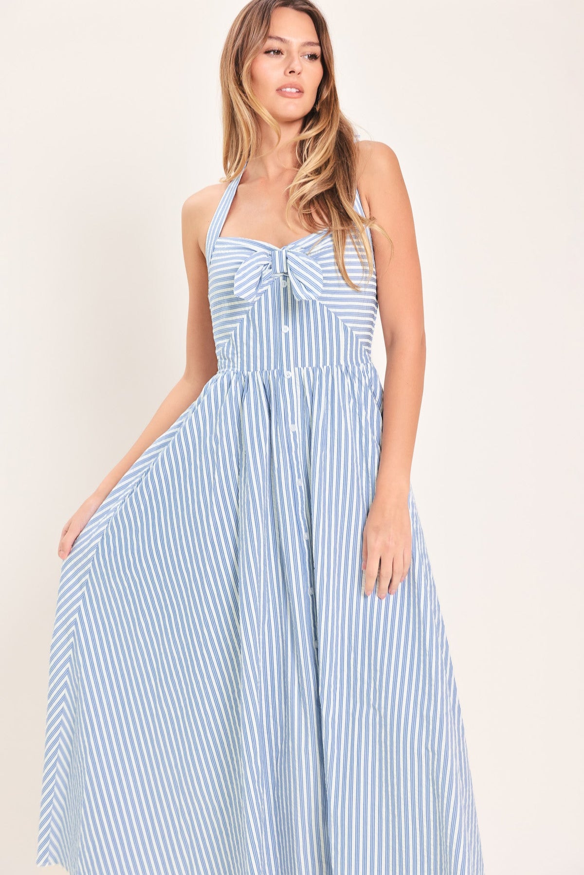 Woman wearing a blue and white striped dress against a plain background