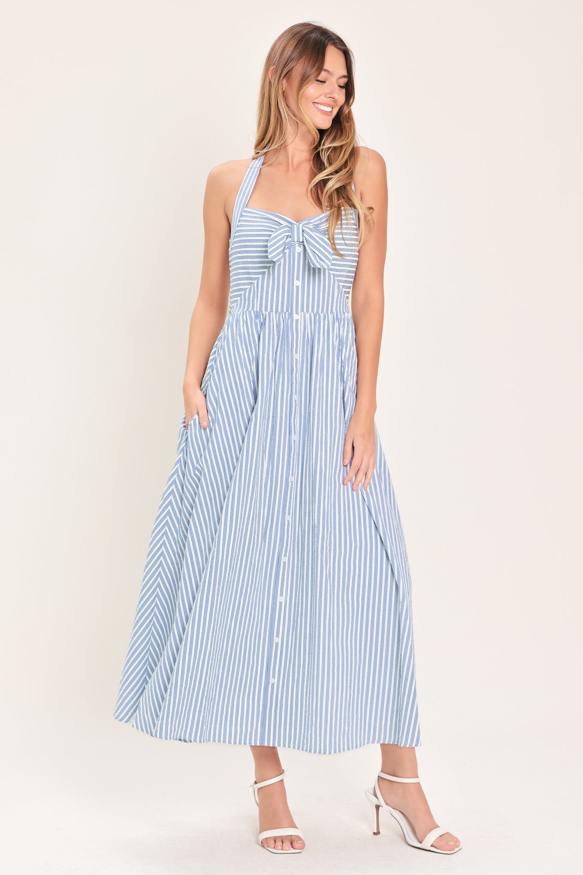 Woman wearing a blue and white striped dress against a plain background