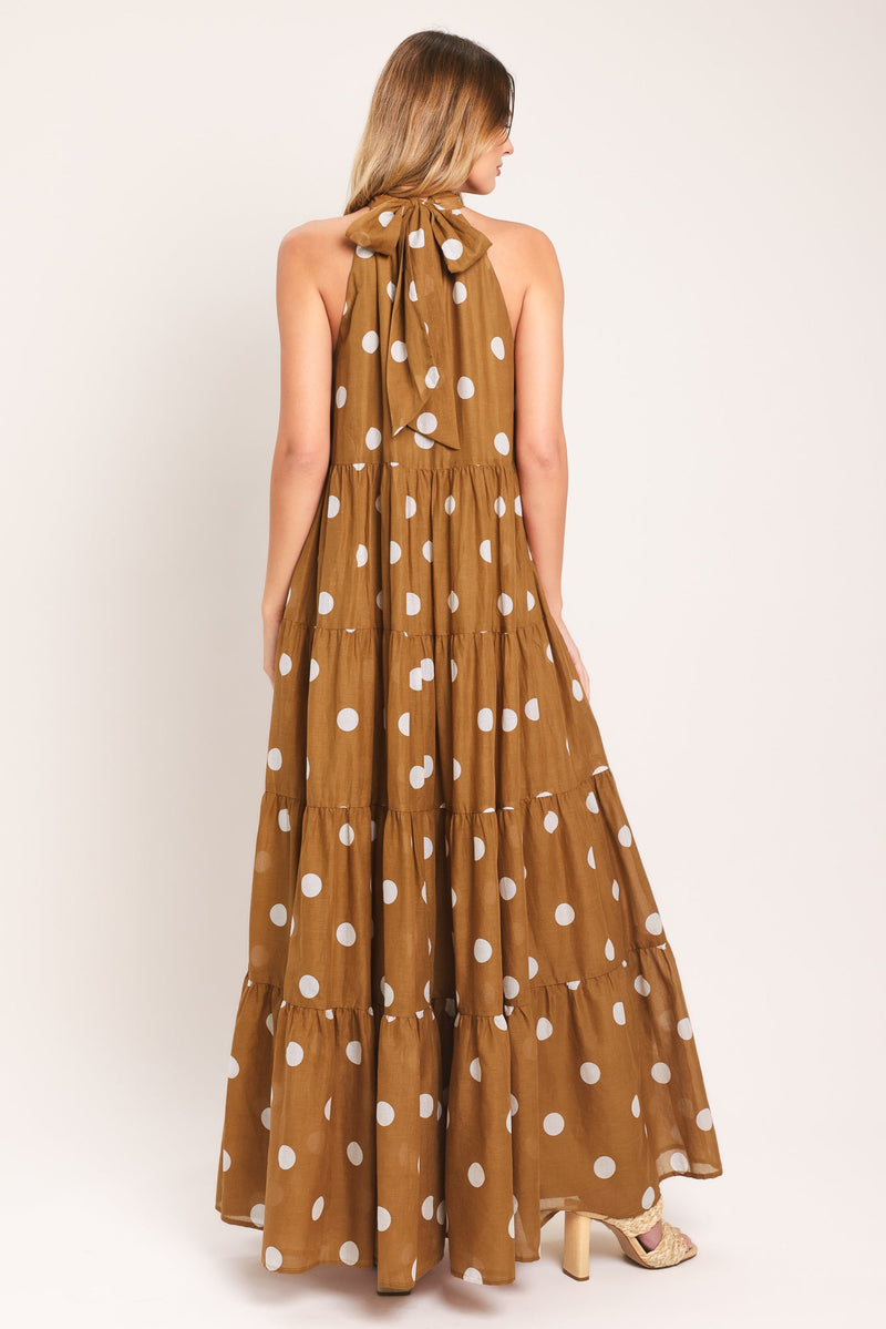 Woman wearing a long brown dress with white polka dots on a white background