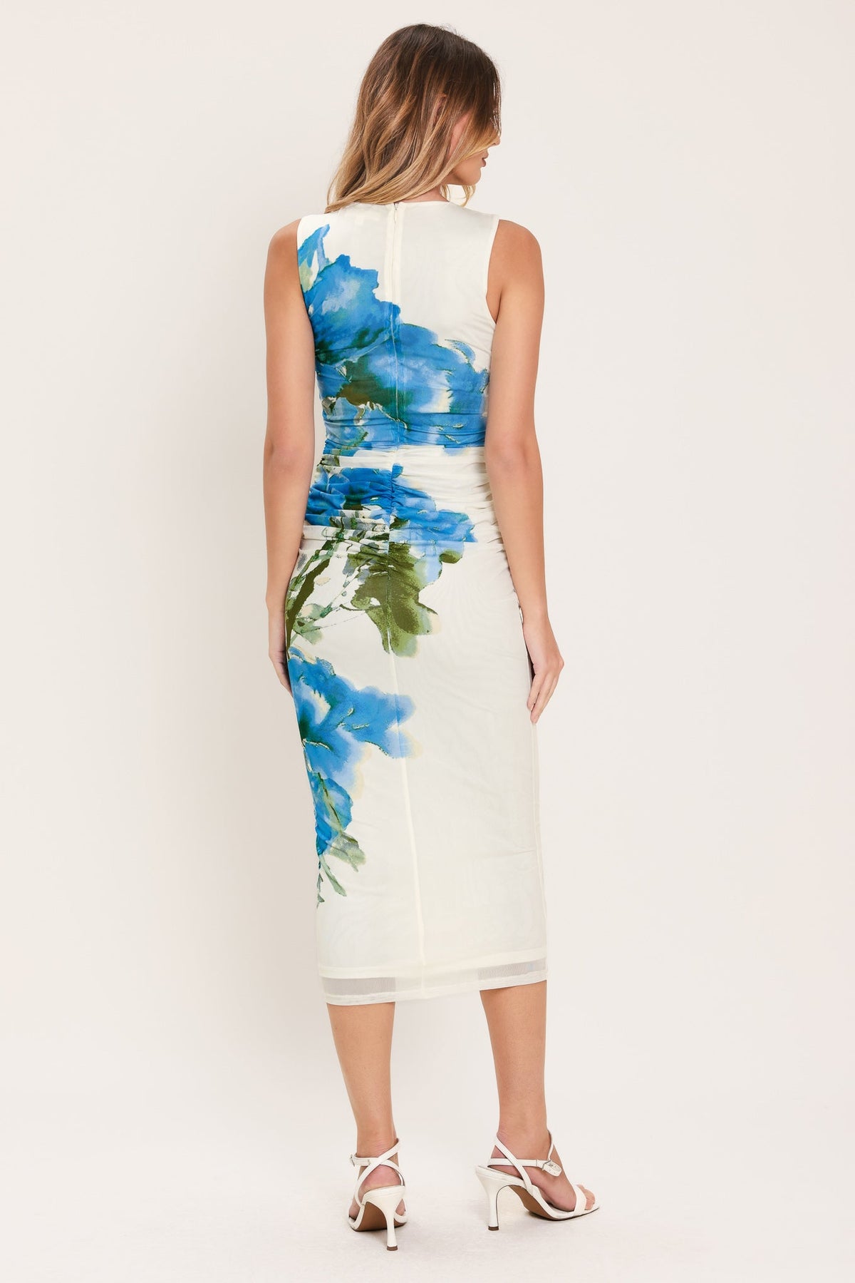 Woman wearing a white dress with blue floral pattern on a plain background