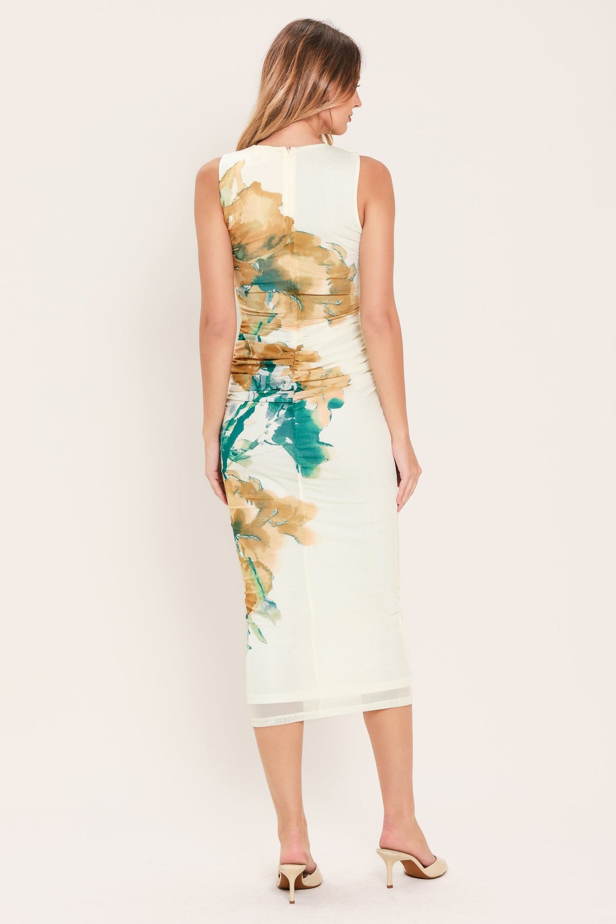 Woman wearing a sleeveless dress with abstract floral design on a plain background