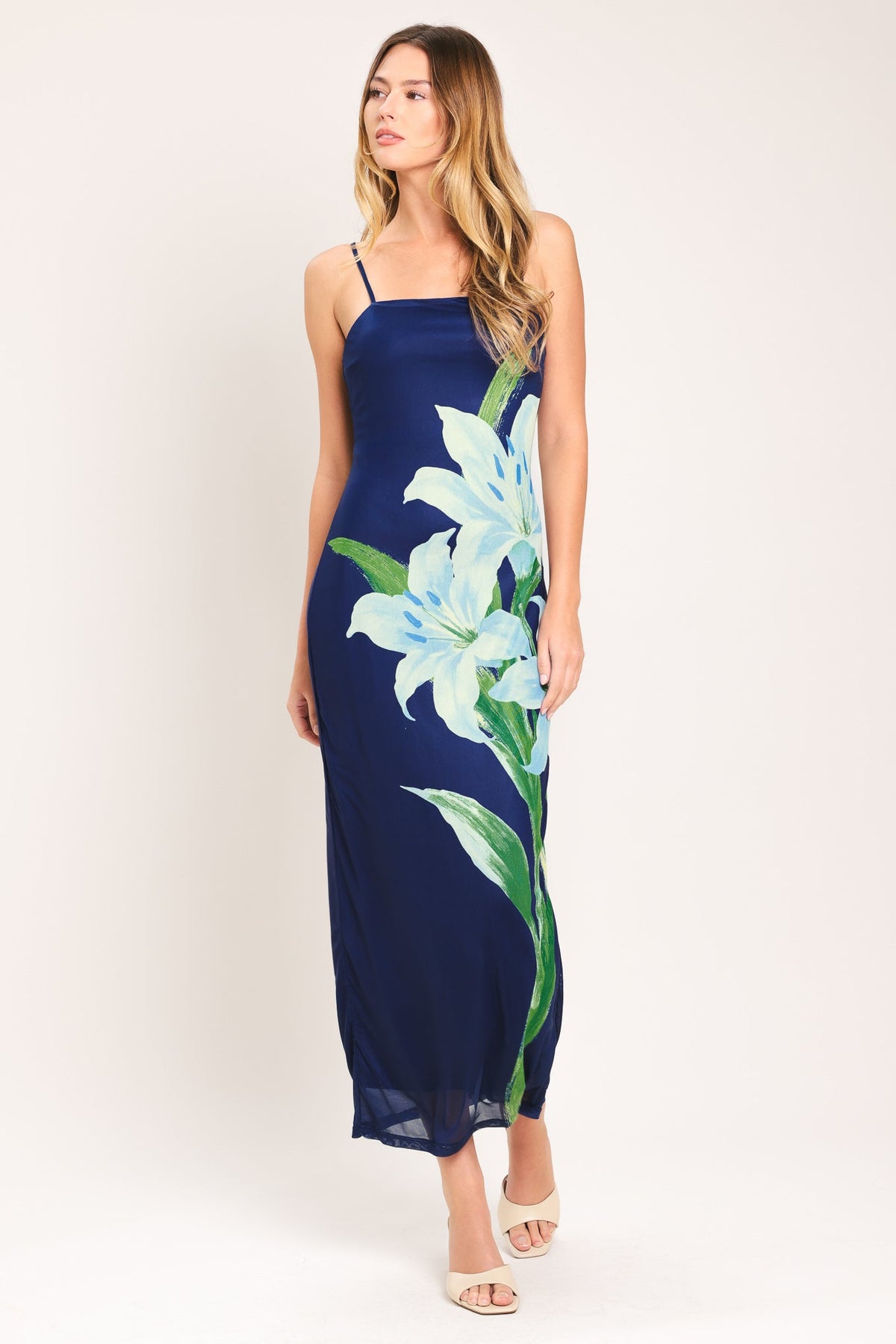 Woman wearing a navy blue dress with floral design on a white background
